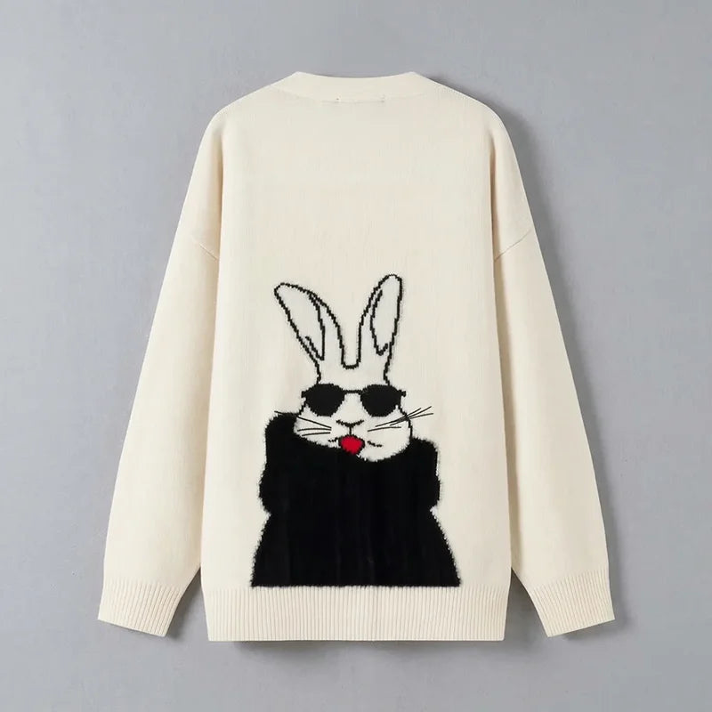 Back view of a cream knit cardigan with a large rabbit motif wearing black sunglasses and a black coat, set against a light grey background.