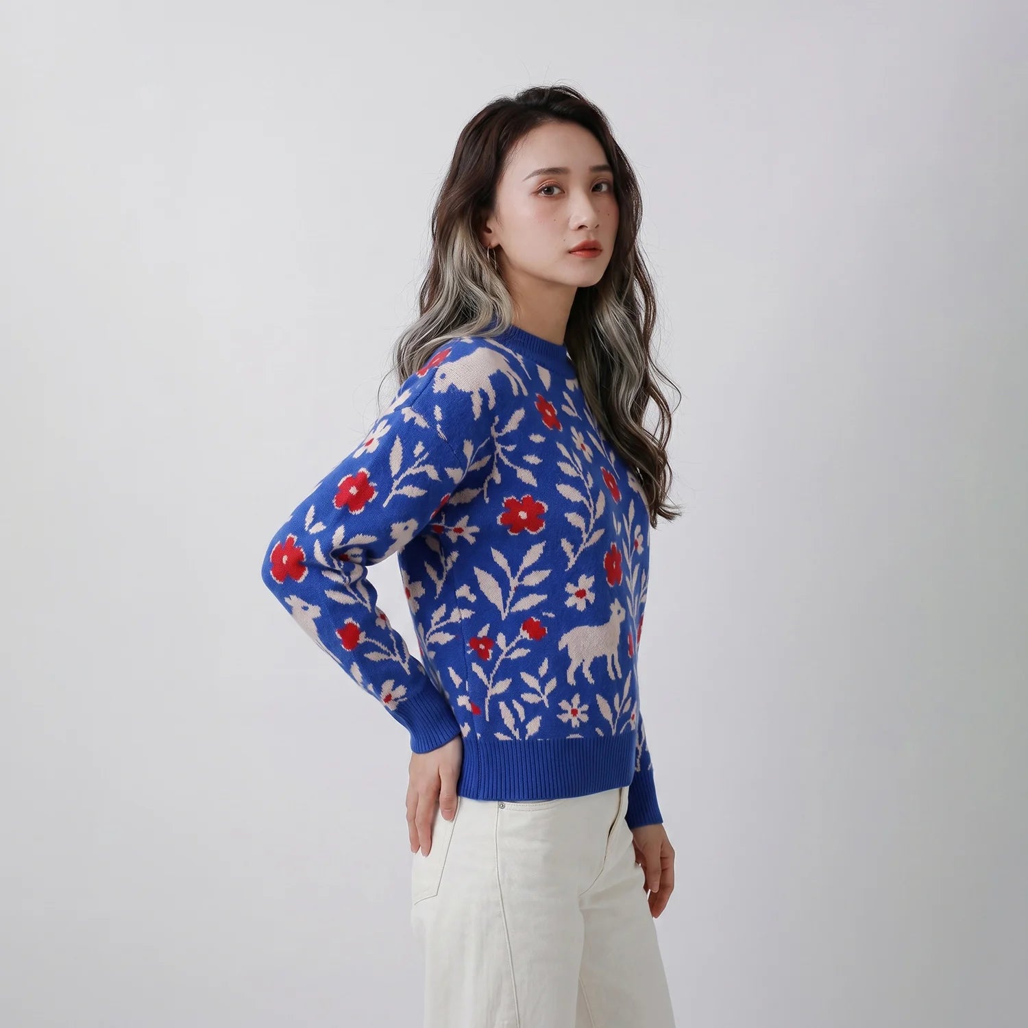 Side view of model wearing a blue merino wool jumper with sheep and floral motifs.