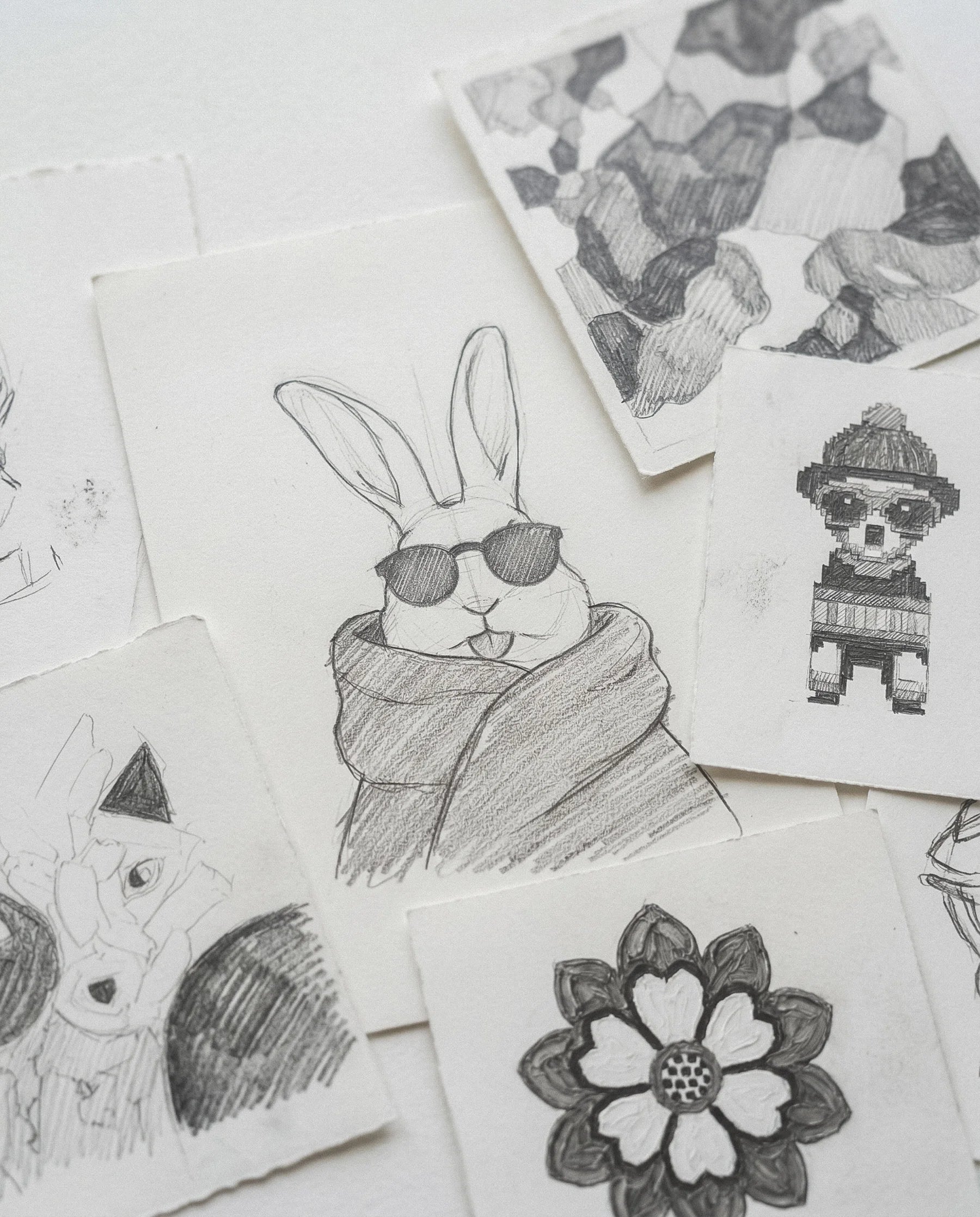Original pencil sketches of a rabbit, flowers and character motifs used in John and Alice knitwear designs.