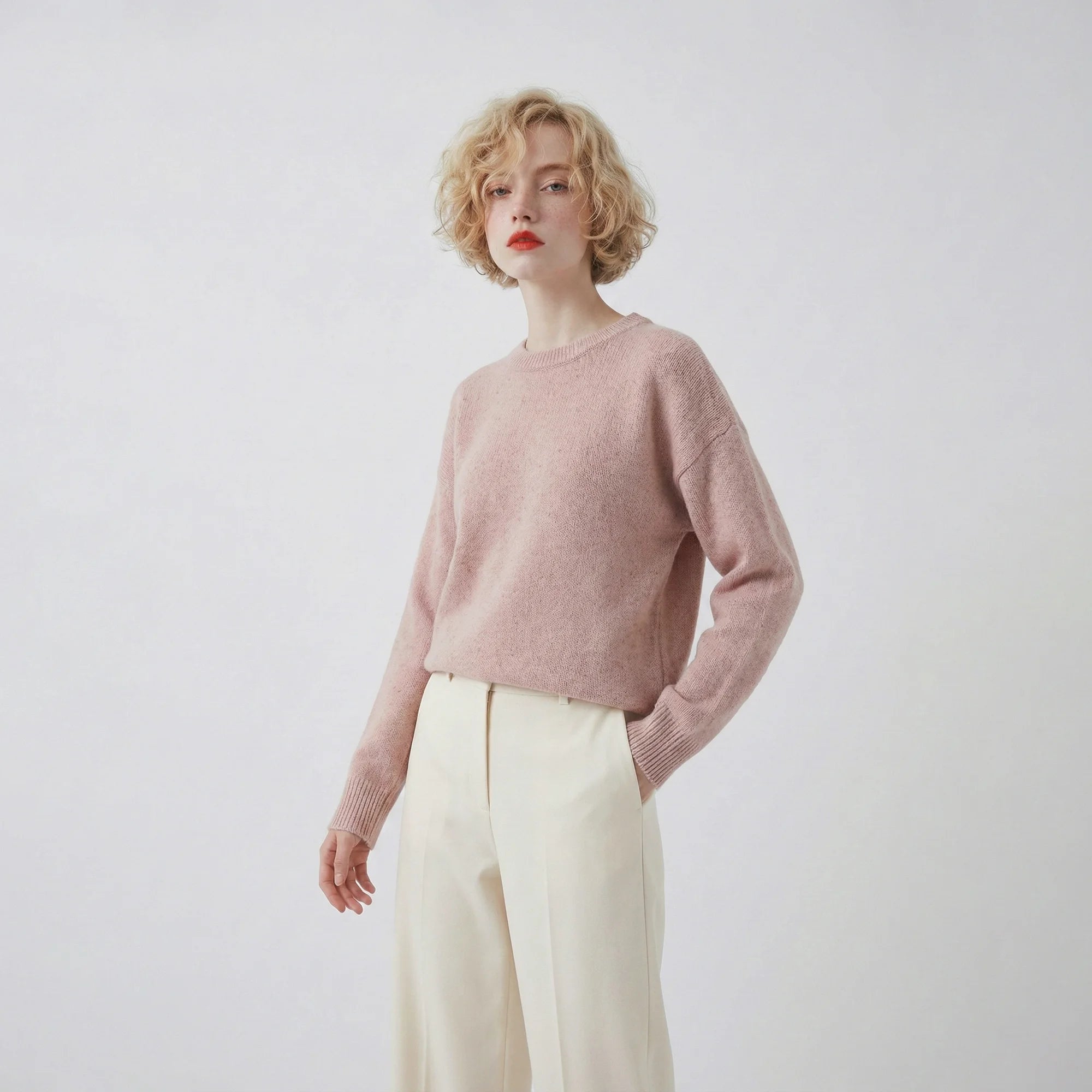 Model wearing a blush pink jumper with a crew neck and a slightly oversized fit.