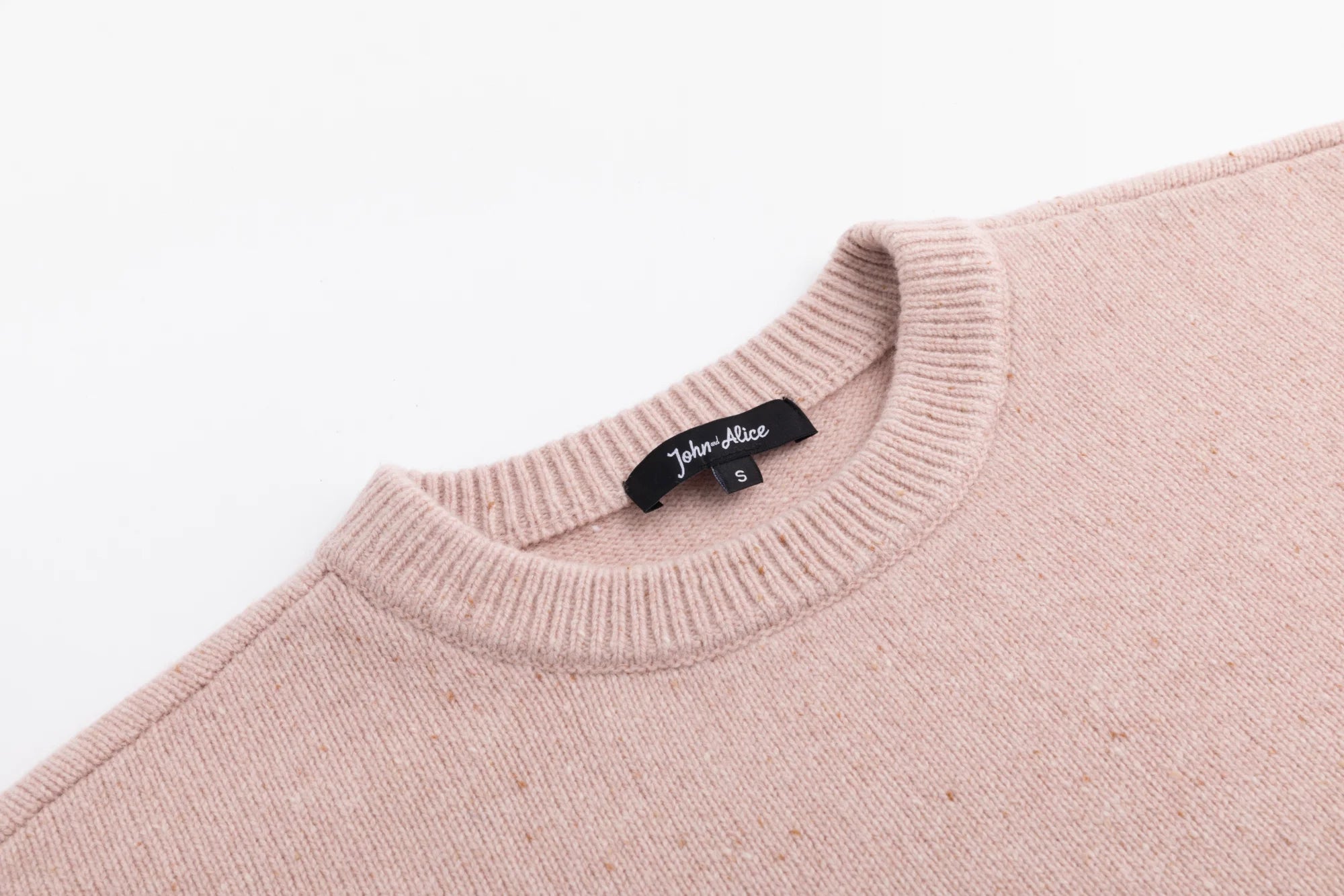 Close-up of the crew neckline on the blush pink jumper.
