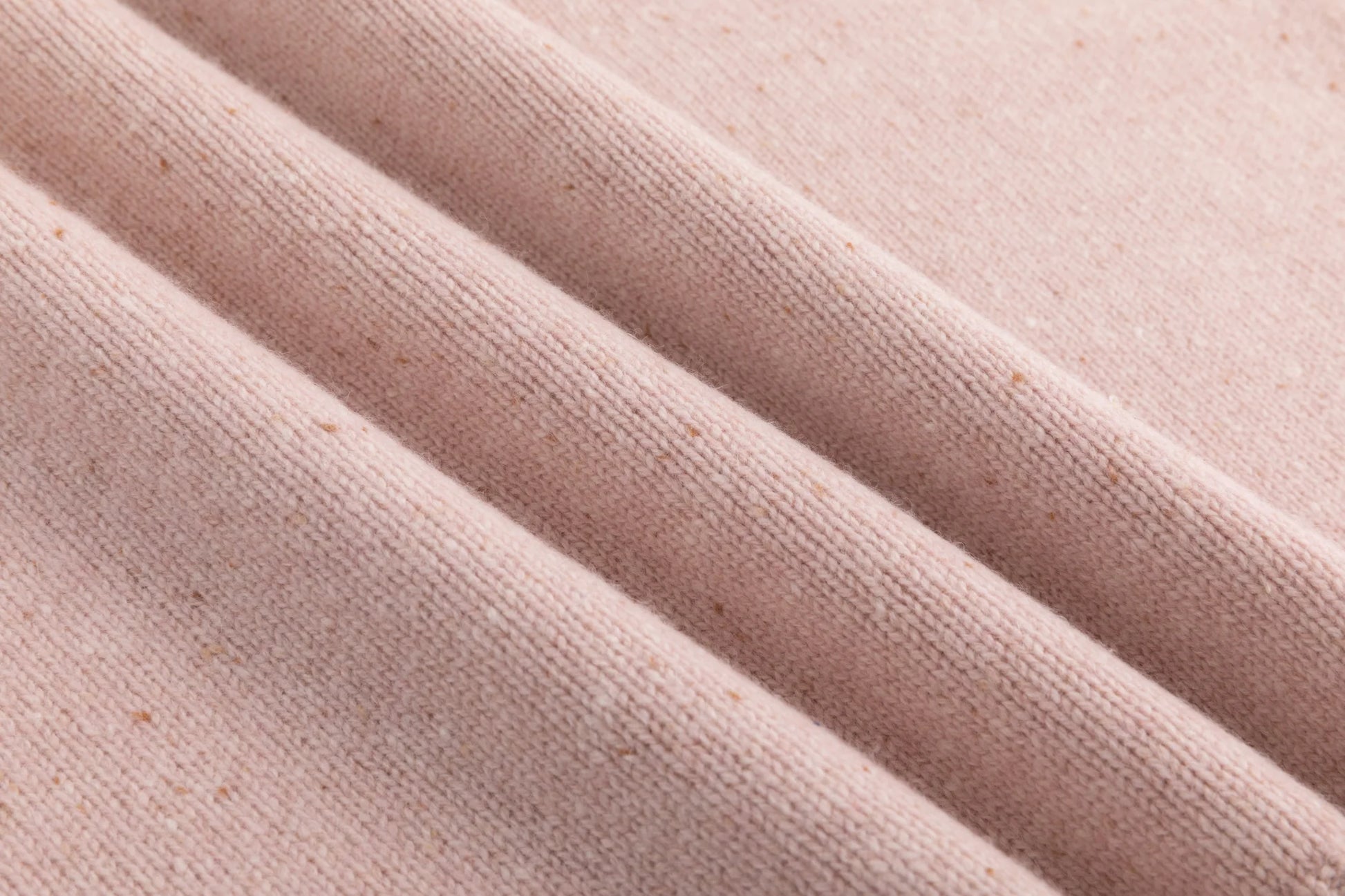 Close-up of the fine speckled knit texture on the blush pink jumper.