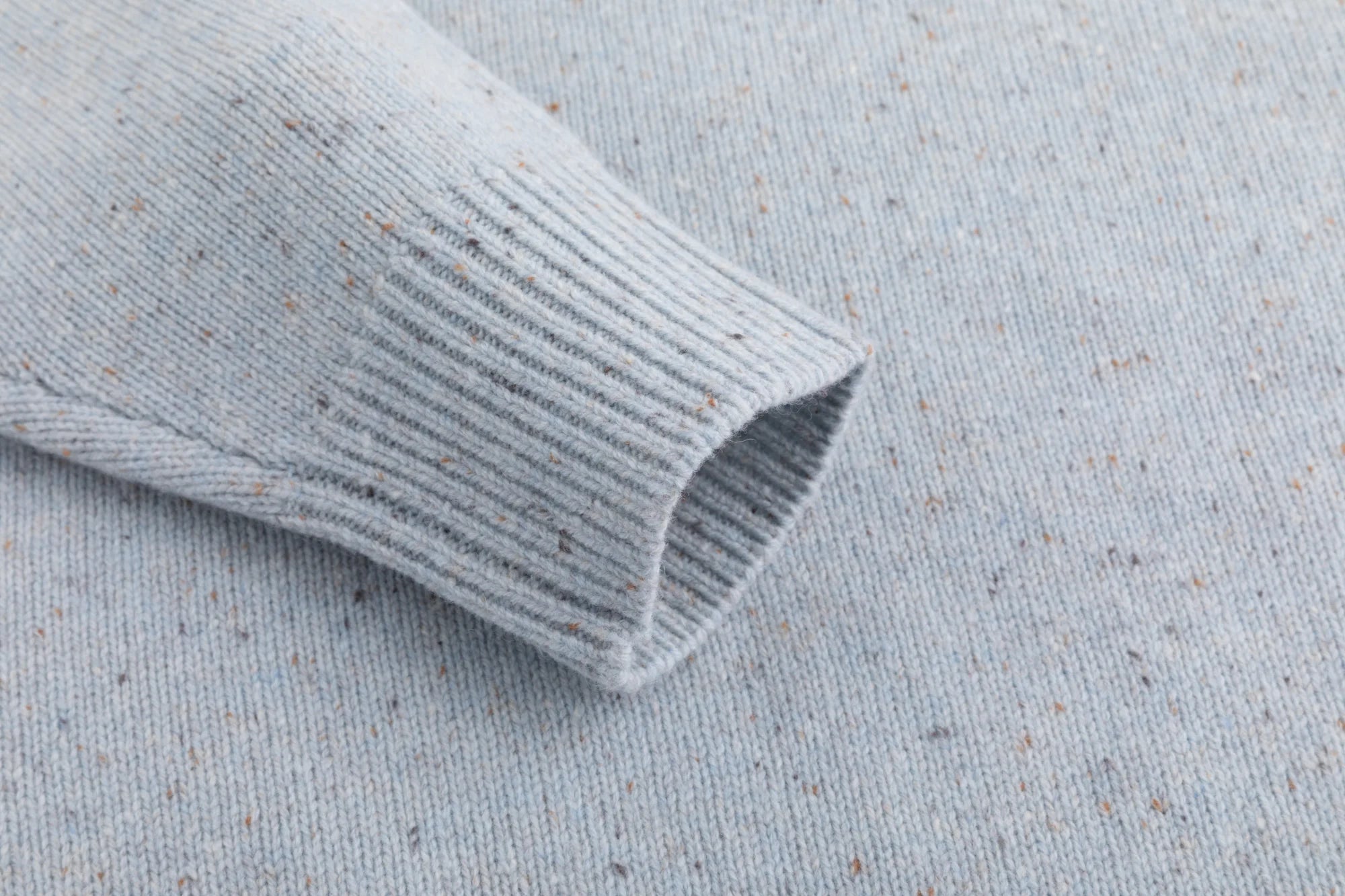 Close-up of the ribbed cuff on the light blue jumper.