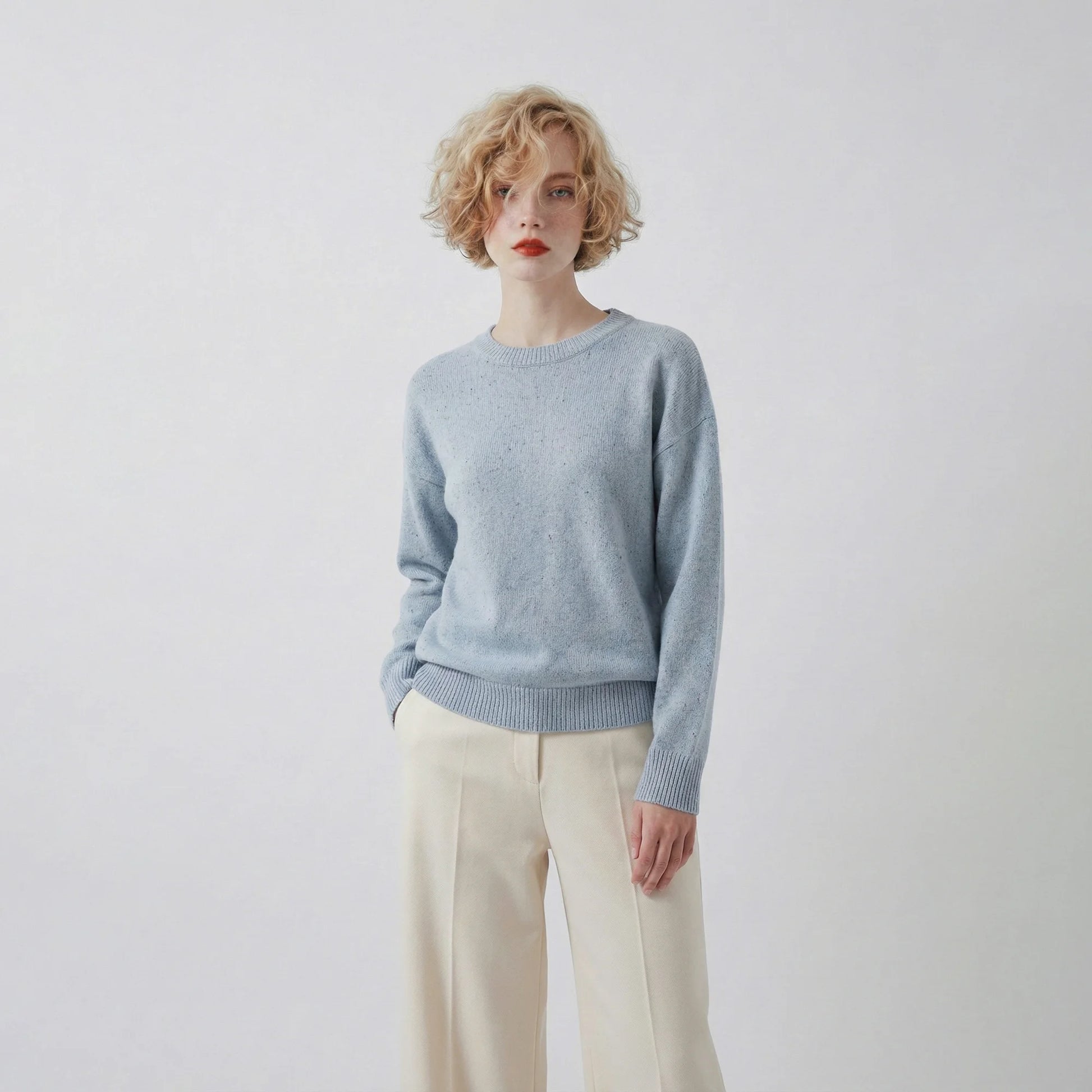 Model wearing a light blue jumper with a crew neck and a slightly oversized fit.