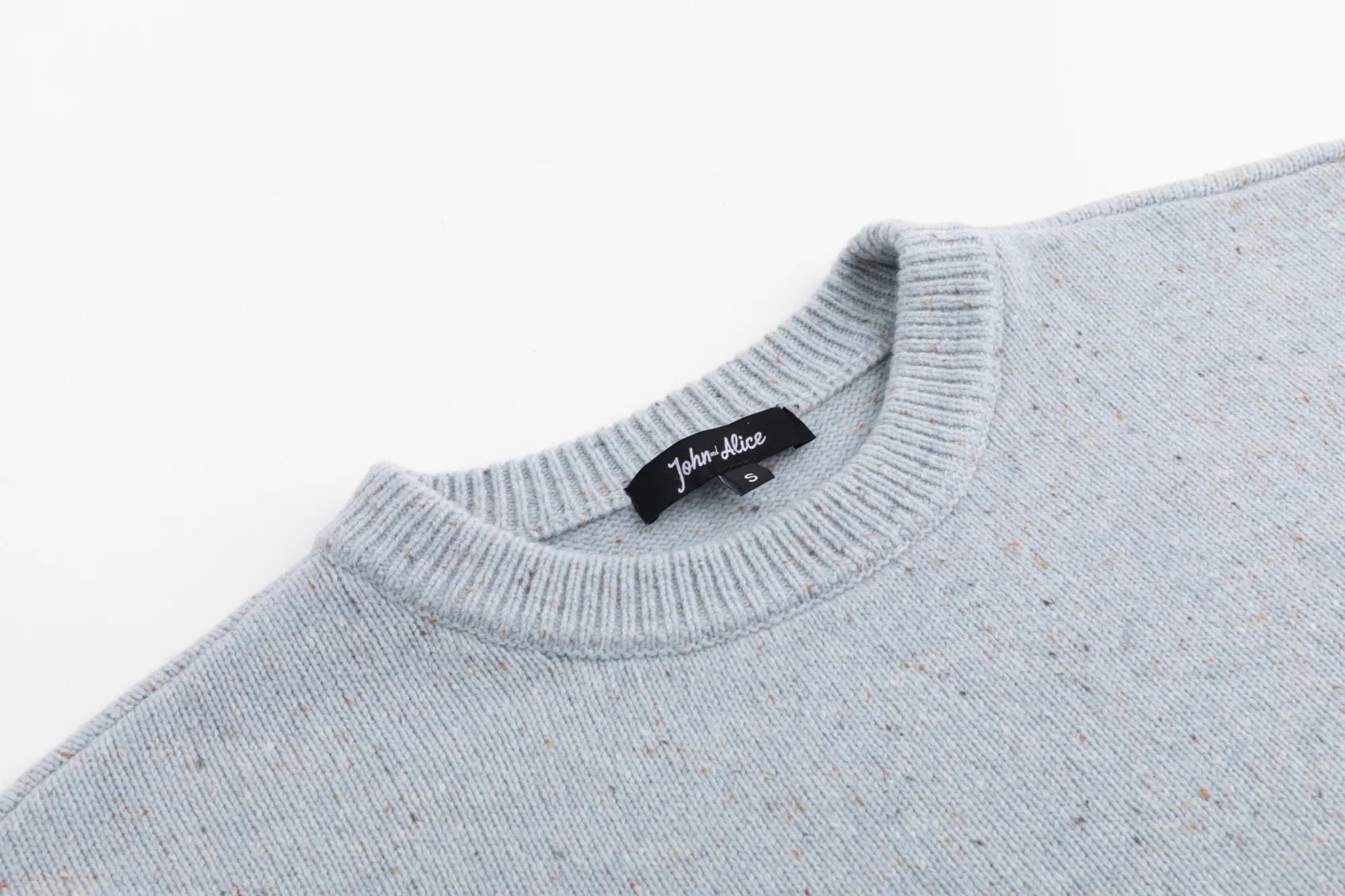 Close-up of the crew neckline on the light blue jumper.