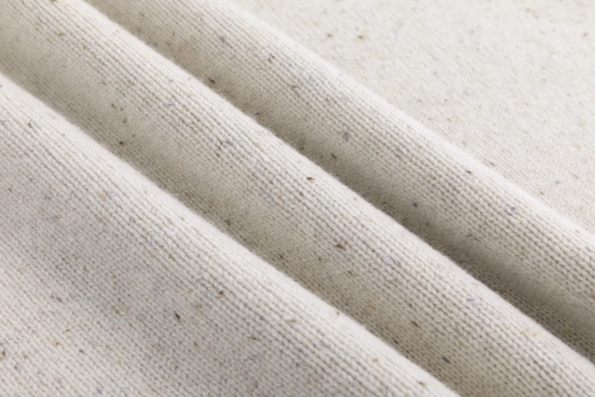 Close-up of the fine speckled knit texture on the oatmeal jumper.