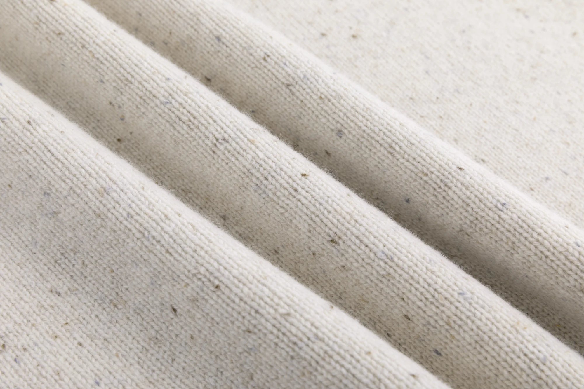 Close-up of the fine speckled knit texture on the oatmeal jumper.