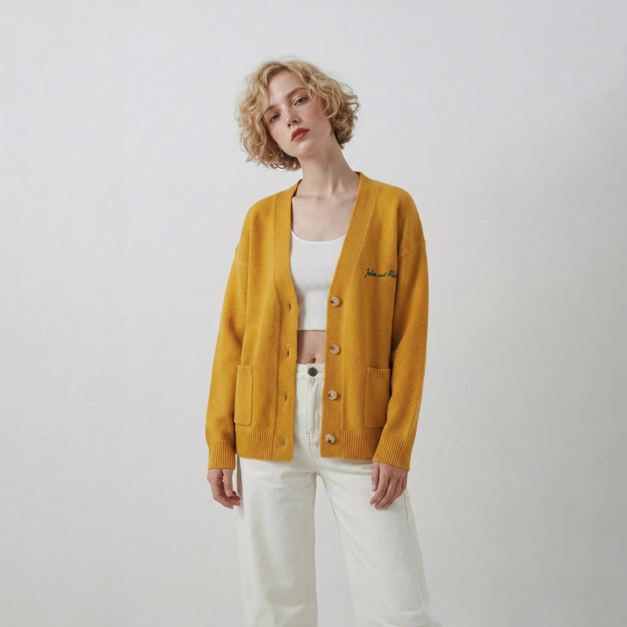 Model front view wearing a mustard yellow cardigan with a V-neck and front patch pockets.