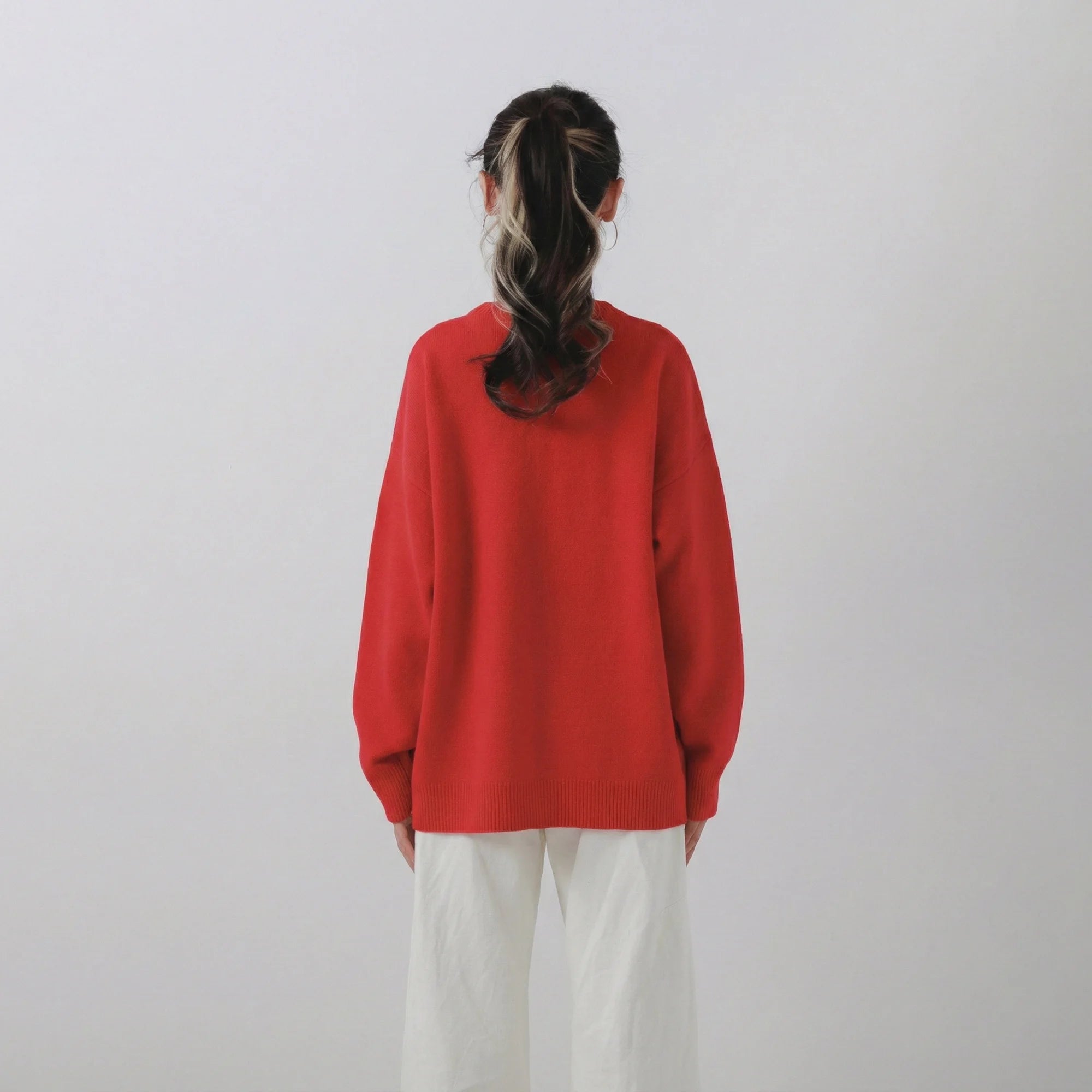 Back view of model wearing a red jumper with an oversized fit and plain back.