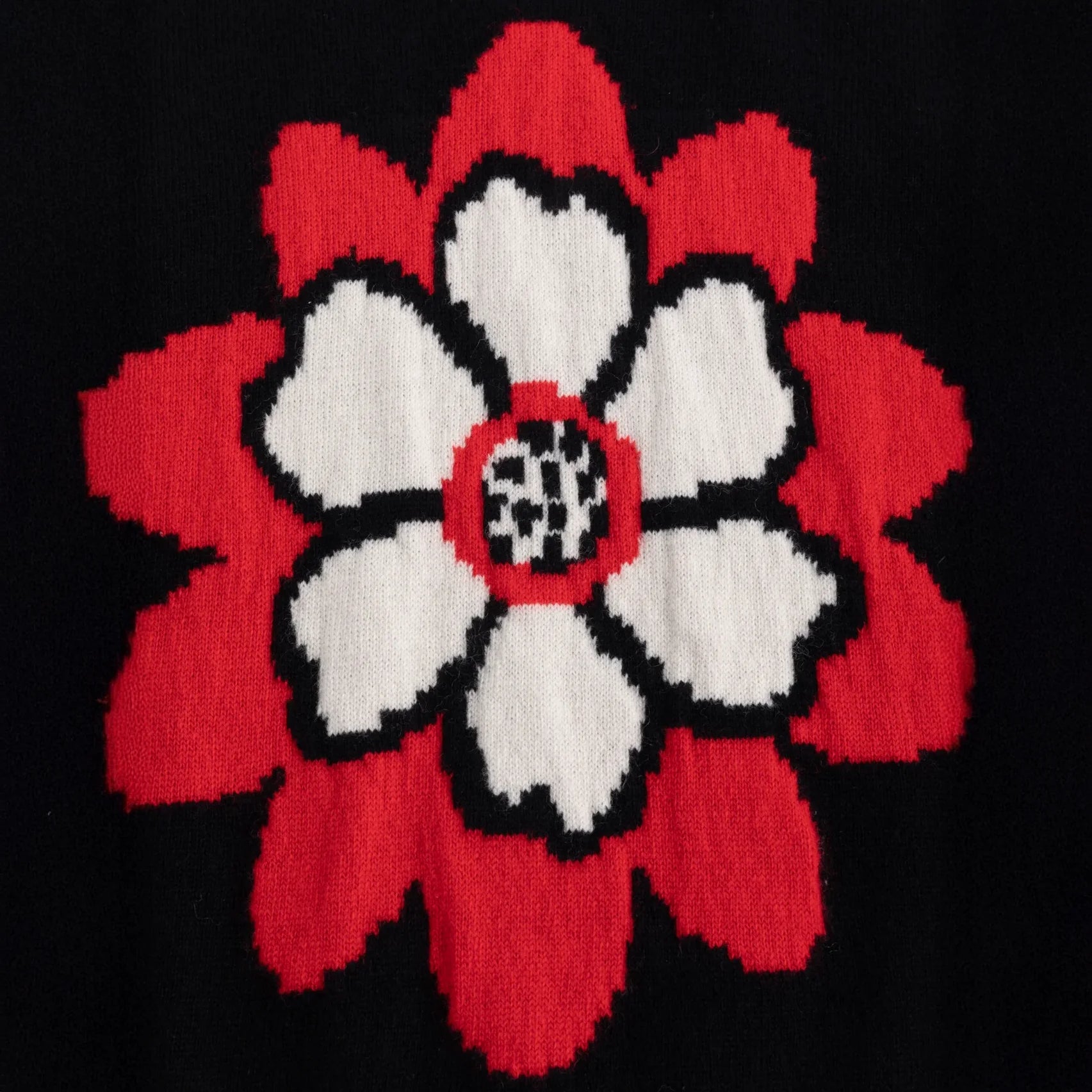 Close-up of the red and white flower intarsia on the black knit top.