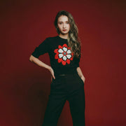 Model wearing a black short-sleeve knit top with an abstract flower jacquard on the front.