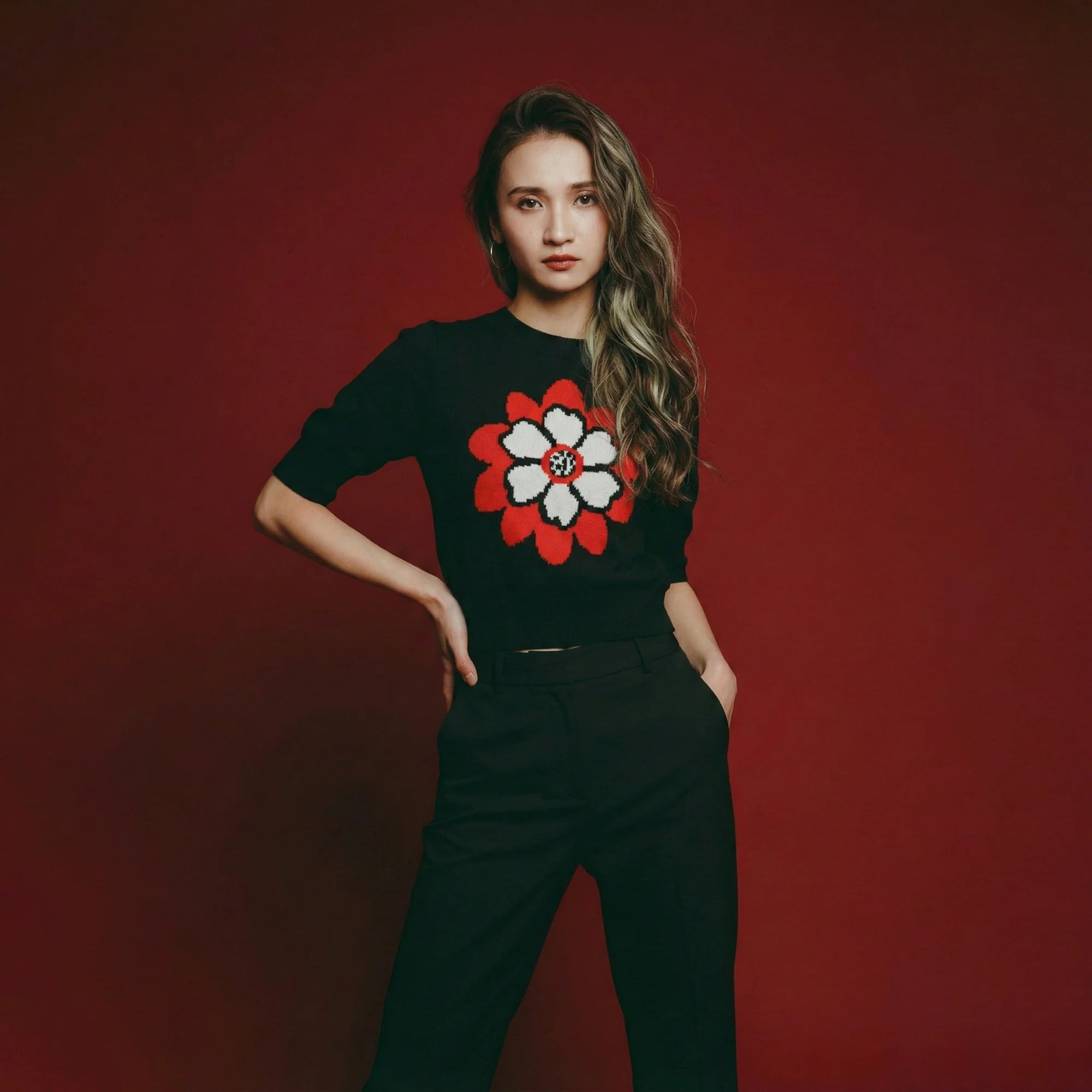 Model wearing a black short-sleeve knit top with an abstract flower jacquard on the front.