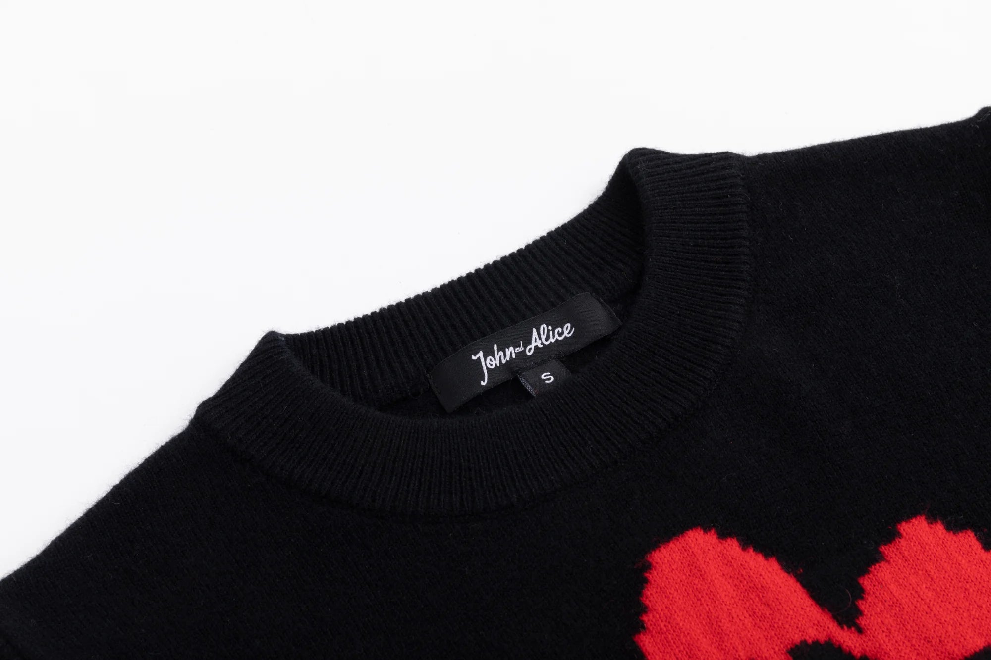 Close-up of the crew neckline and front flower jacquard on the black knit top.