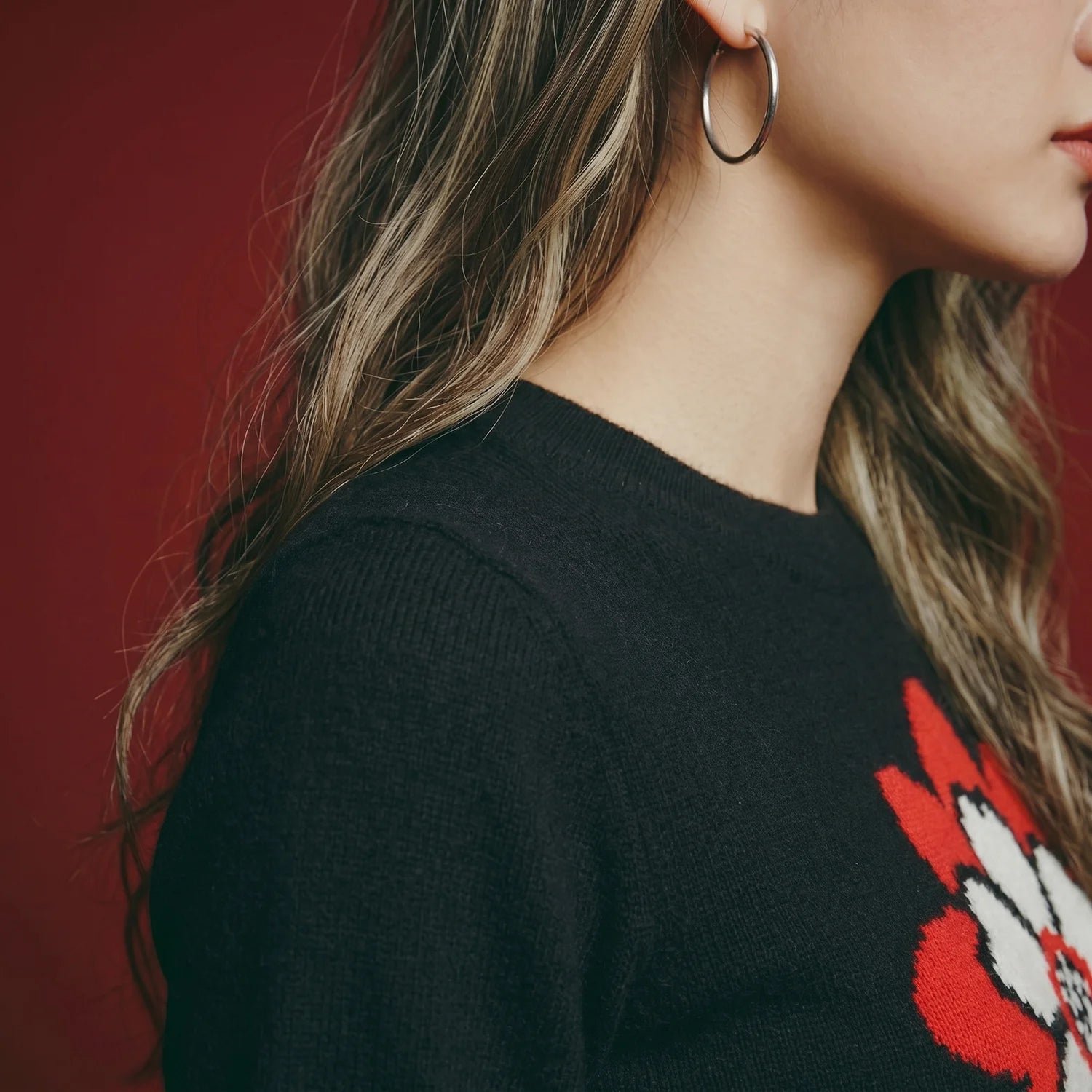 Close-up of the neckline and shoulder on a black knit top with part of the flower motif.
