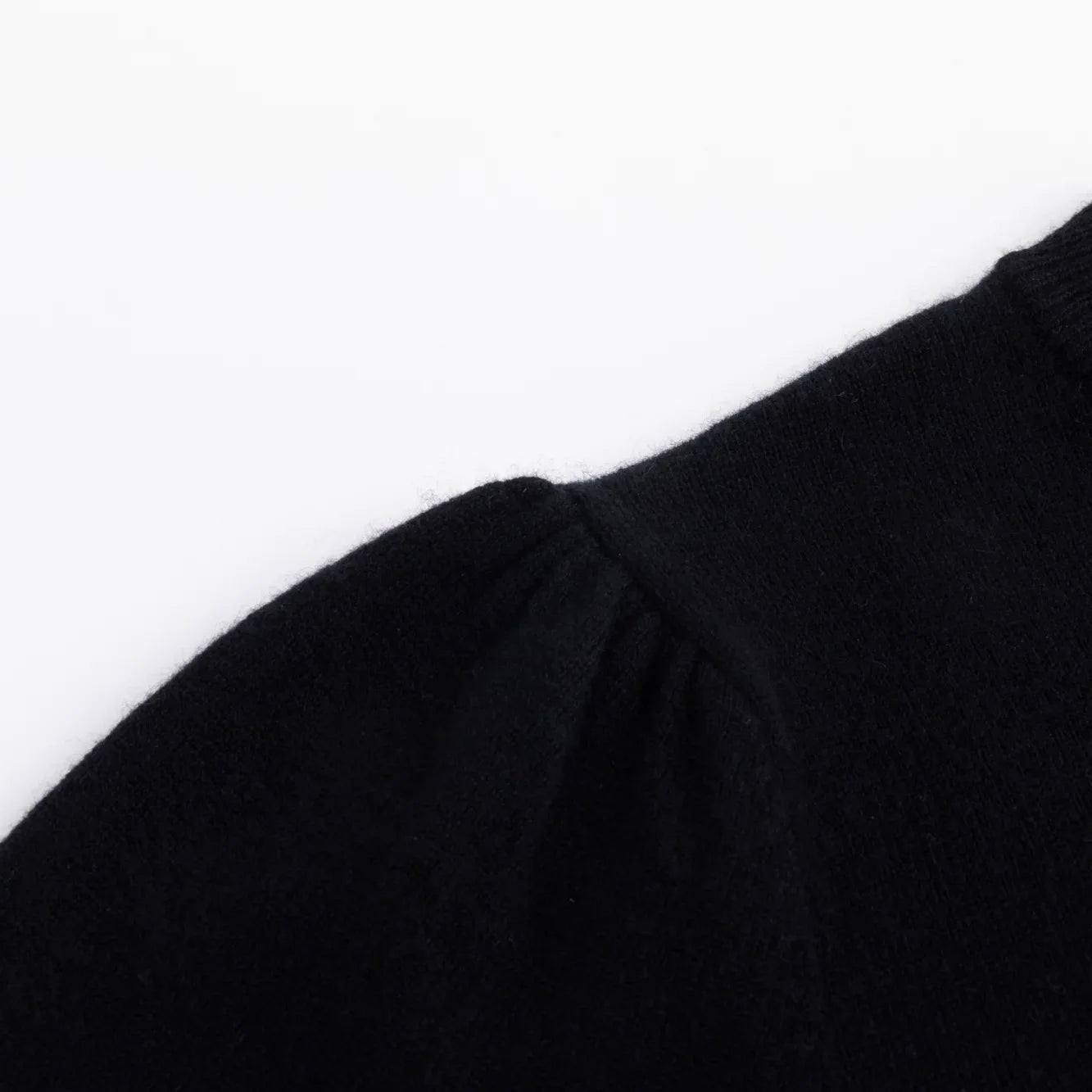 Close-up of the shoulder seam and smooth knit texture on the black top.