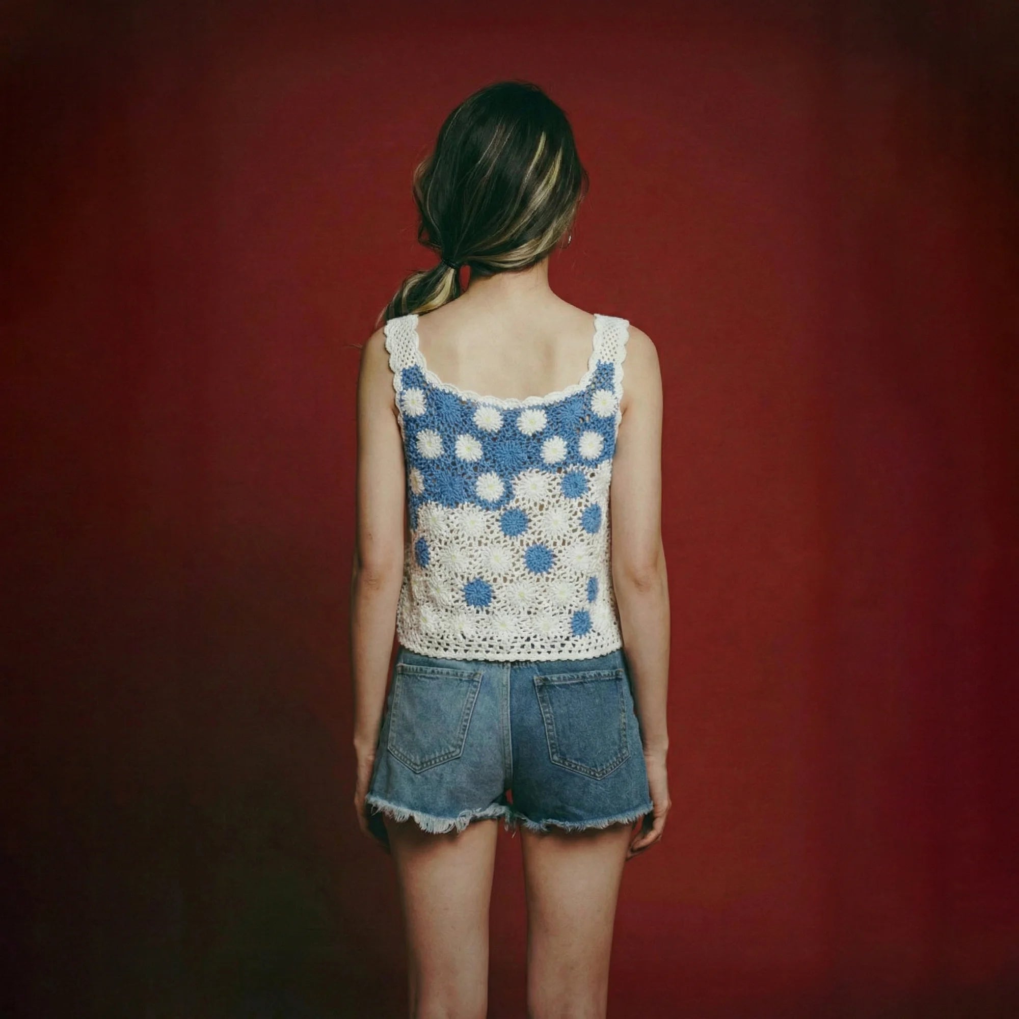 Back view of model wearing a blue and white crochet camisole top with floral motifs.
