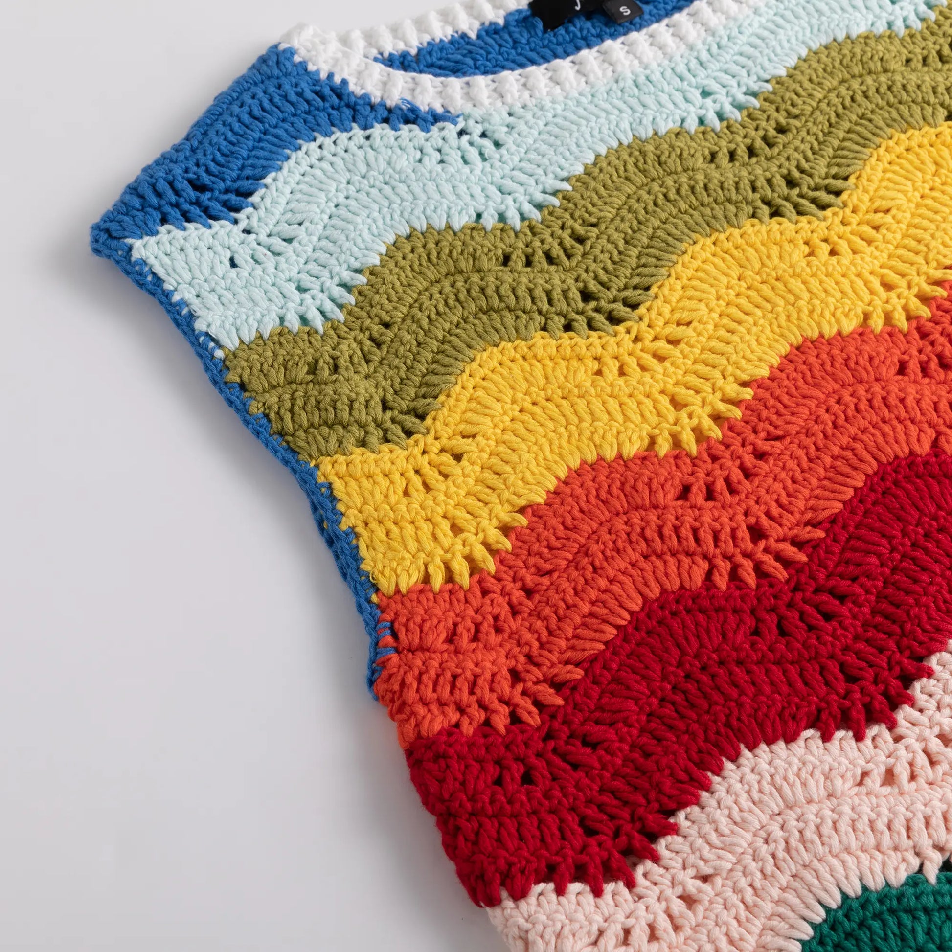 Close-up of the upper front and armhole of the crochet top showing multicolour wave stripes.