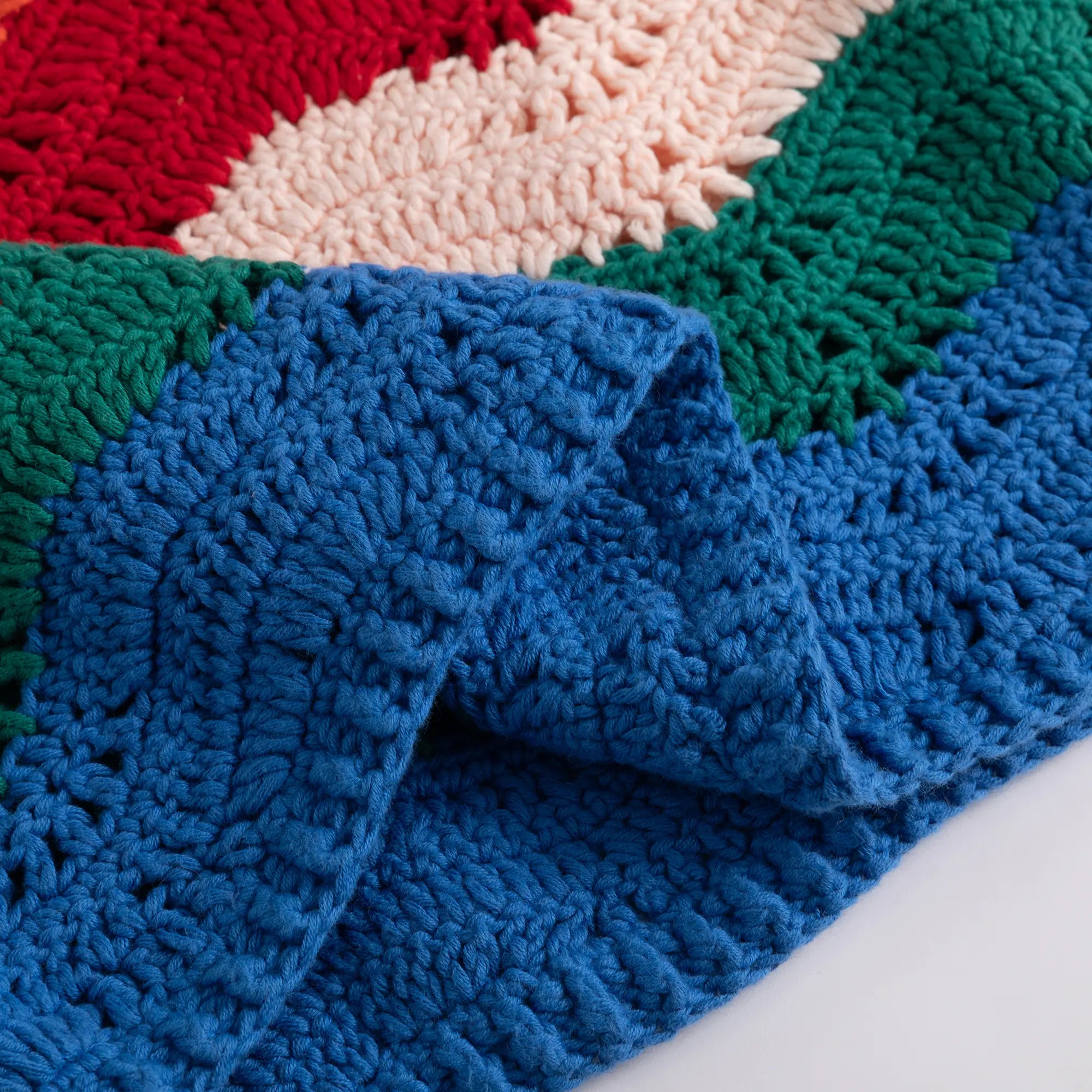 Close-up of the folded crochet fabric showing the multicolour wave pattern and openwork texture.