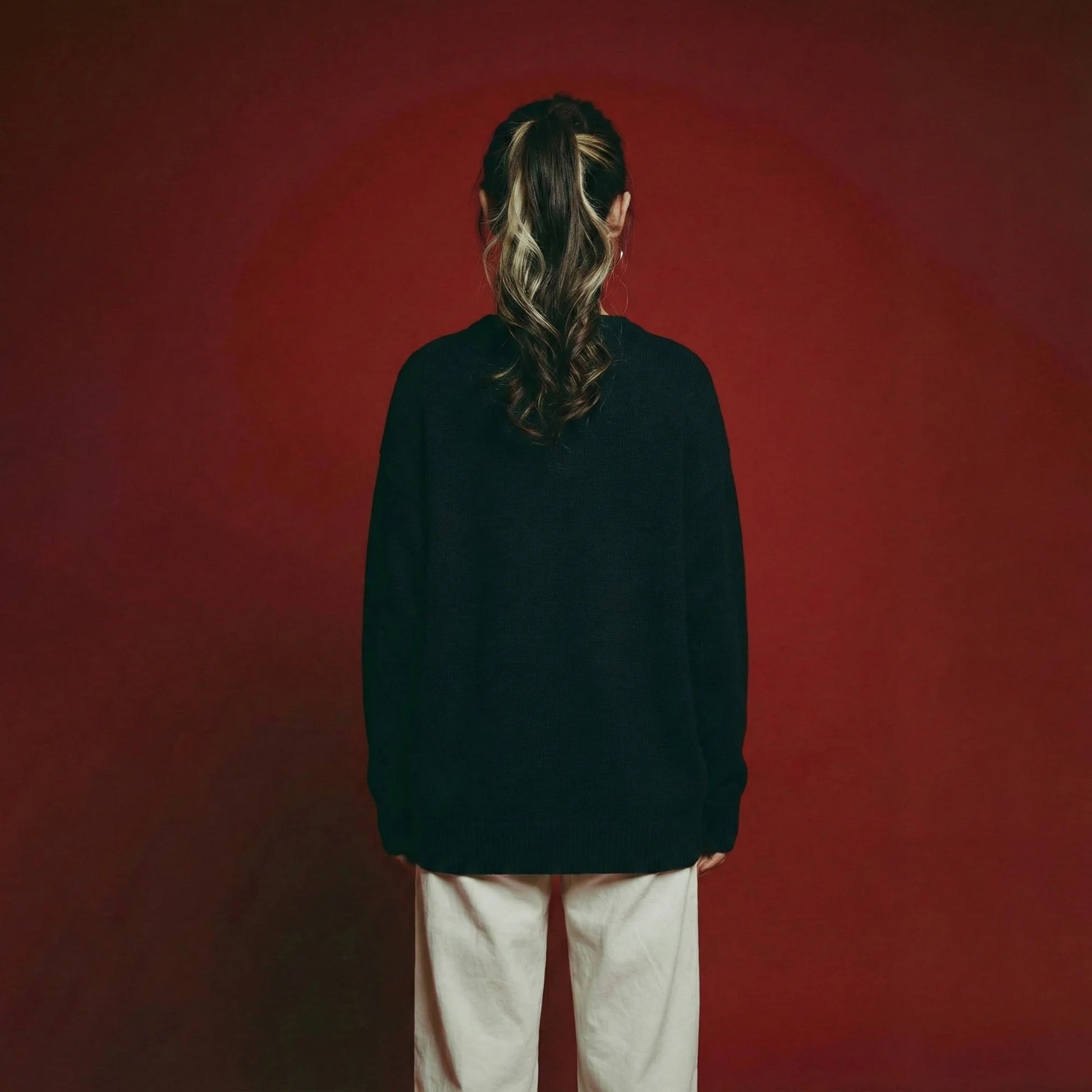 Back view of model wearing a navy oversized jumper with a plain back and ribbed trims.