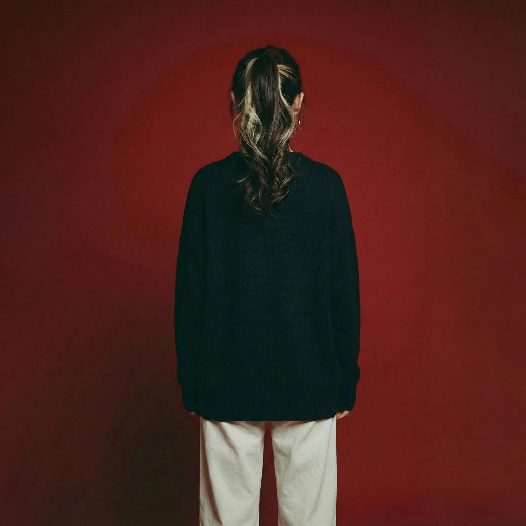 Back view of model wearing a navy oversized jumper with a plain back and ribbed trims.