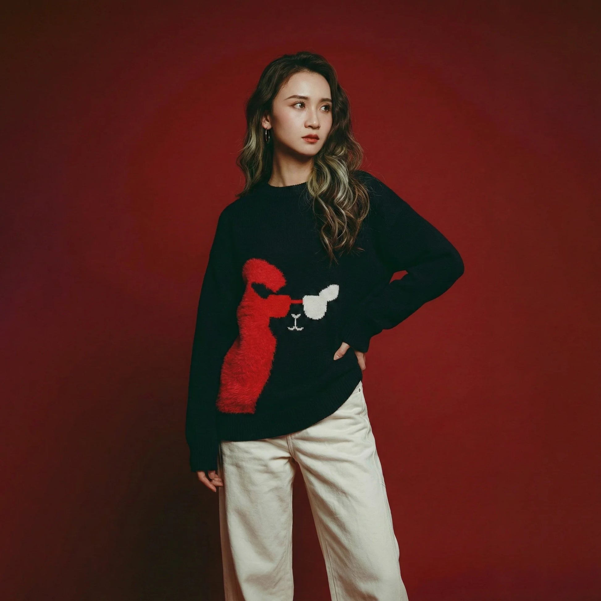 Model wearing a navy oversized intarsia jumper with a llama face motif and a bright red fuzzy heart panel.