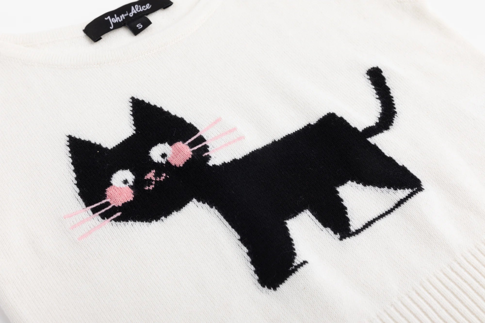 Close-up of the black cat jacquard with pink cheeks and whiskers on the ivory knit tank.