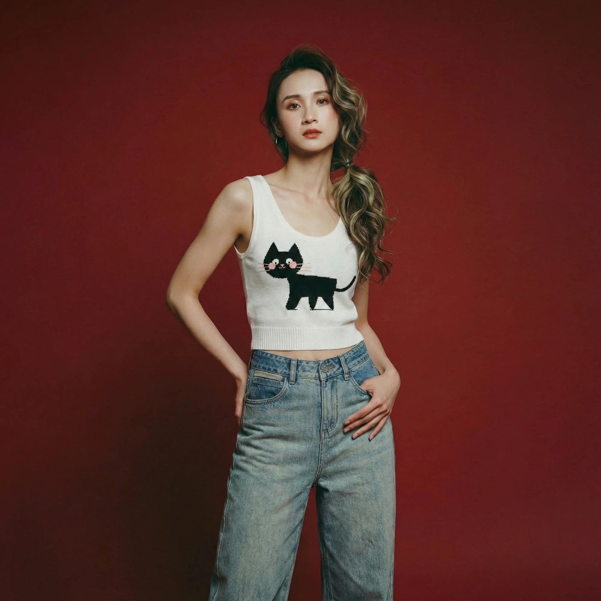Woman wearing an ivory knit tank with a scoop neckline and black cat jacquard on the front.