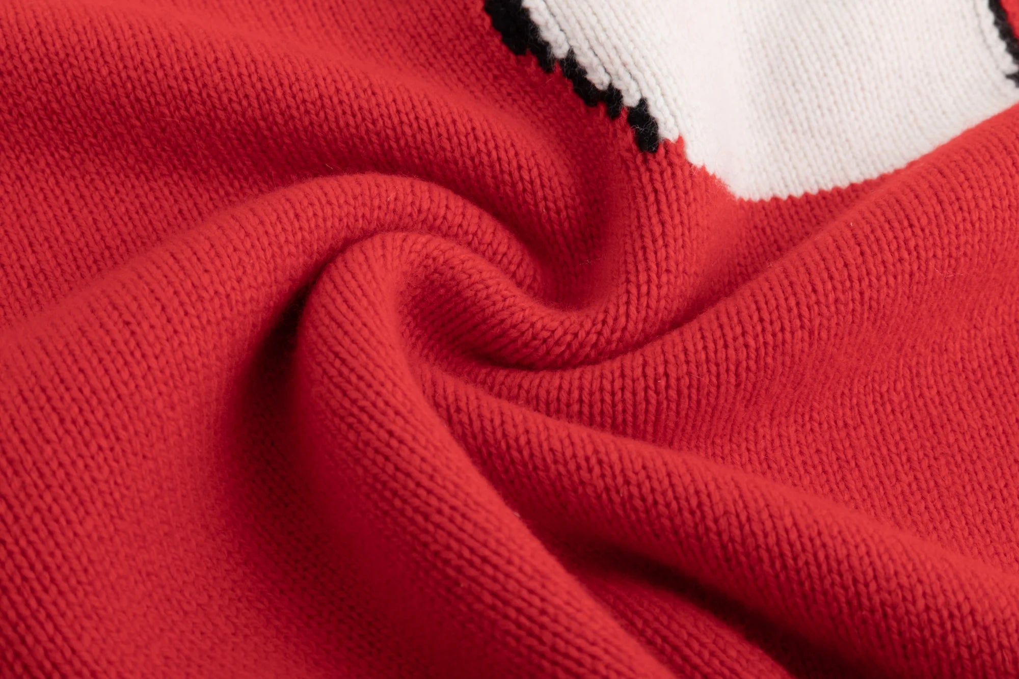 Close-up of the thick knit texture in the cotton and wool blend fabric on the red jumper.