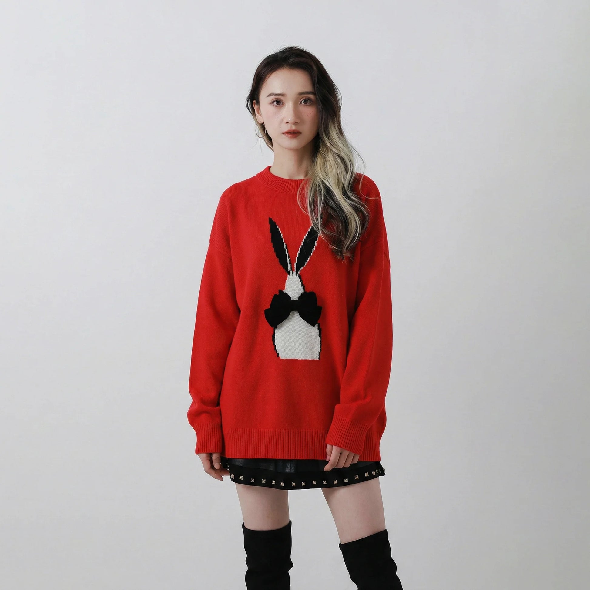 Model wearing a red wool blend jumper with an oversized fit and an abstract rabbit jacquard with a black velvet bow on the front.