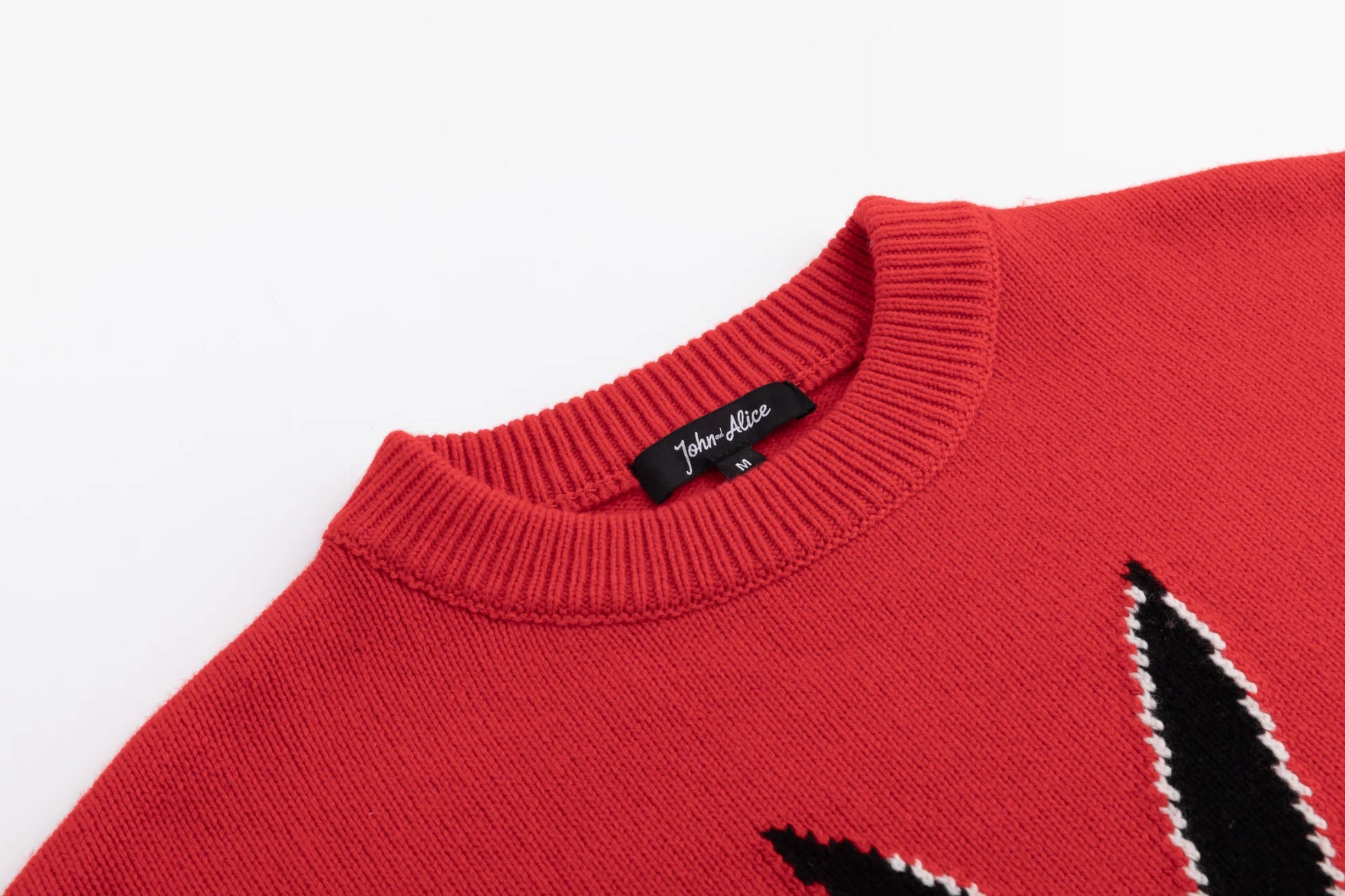 Close-up of the crew neckline and shoulder on the red jumper, with part of the rabbit motif visible.