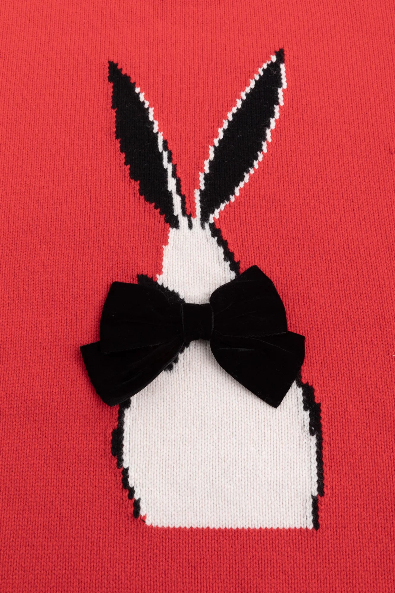 Close-up of the abstract rabbit jacquard with a black velvet bow on the red jumper.
