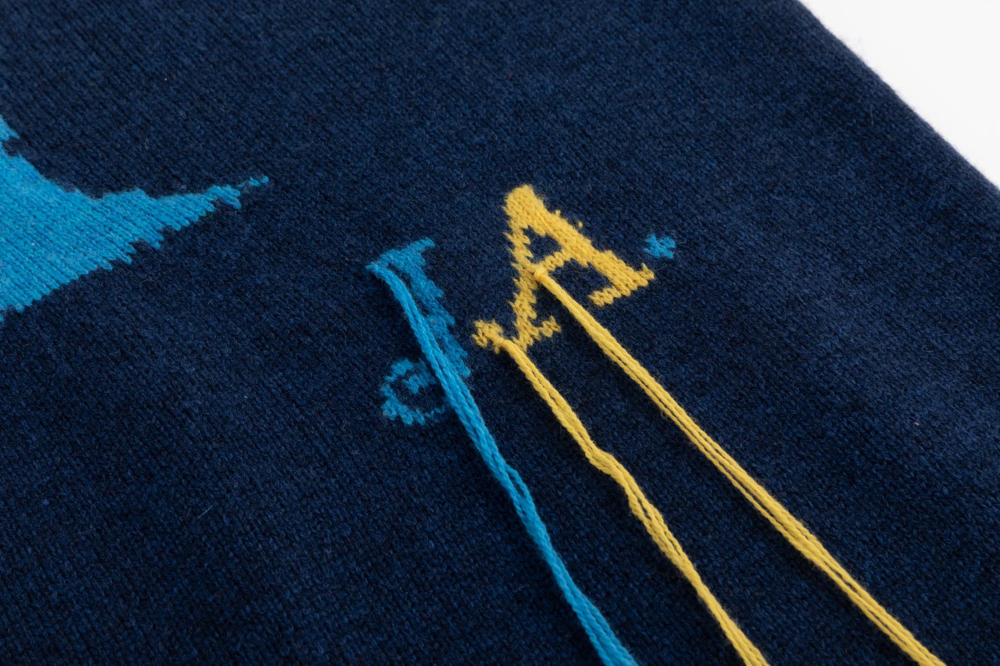 Close-up of the JA logo and tassel detail on a navy jumper.