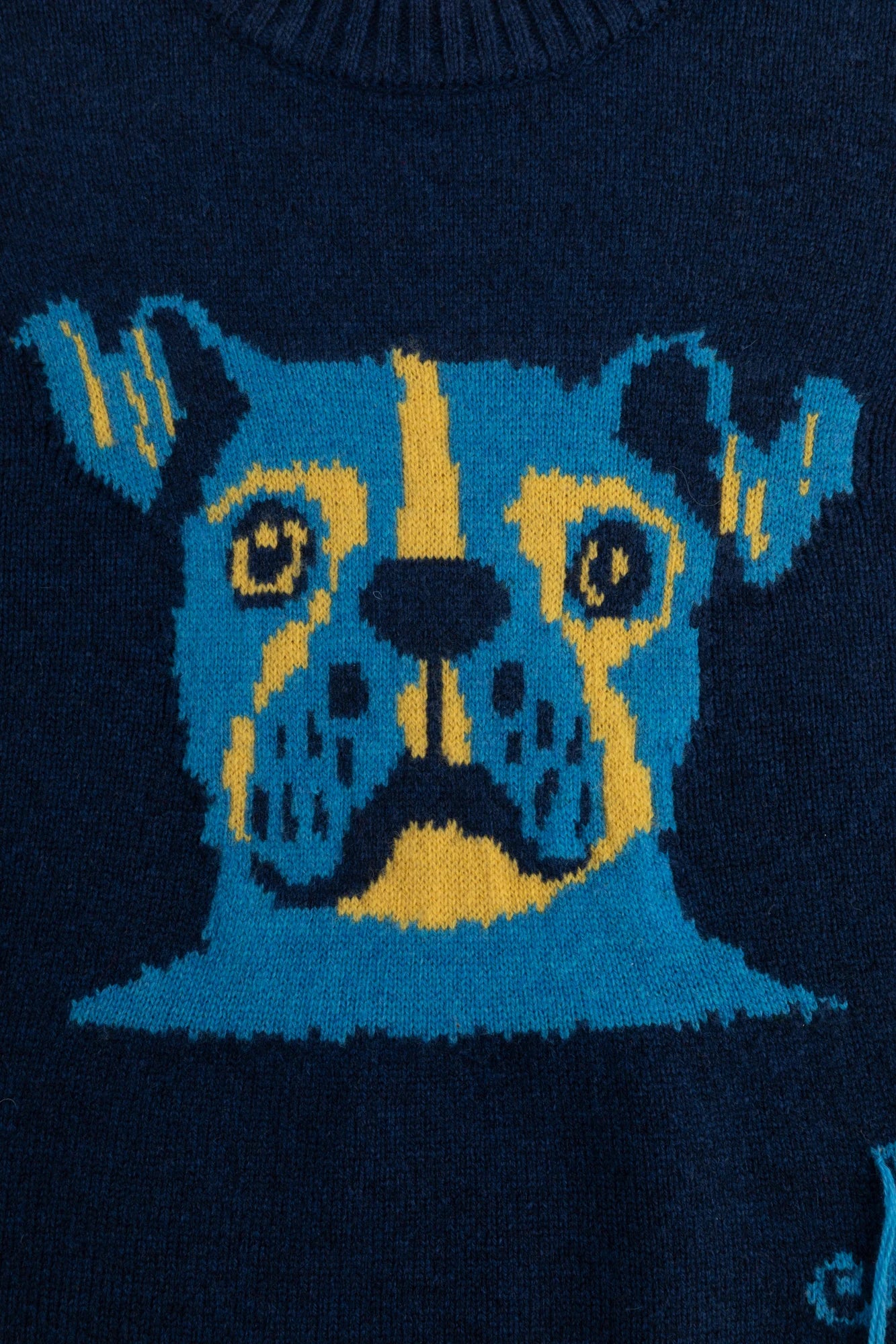 Close-up of the abstract dog face jacquard on a navy jumper.