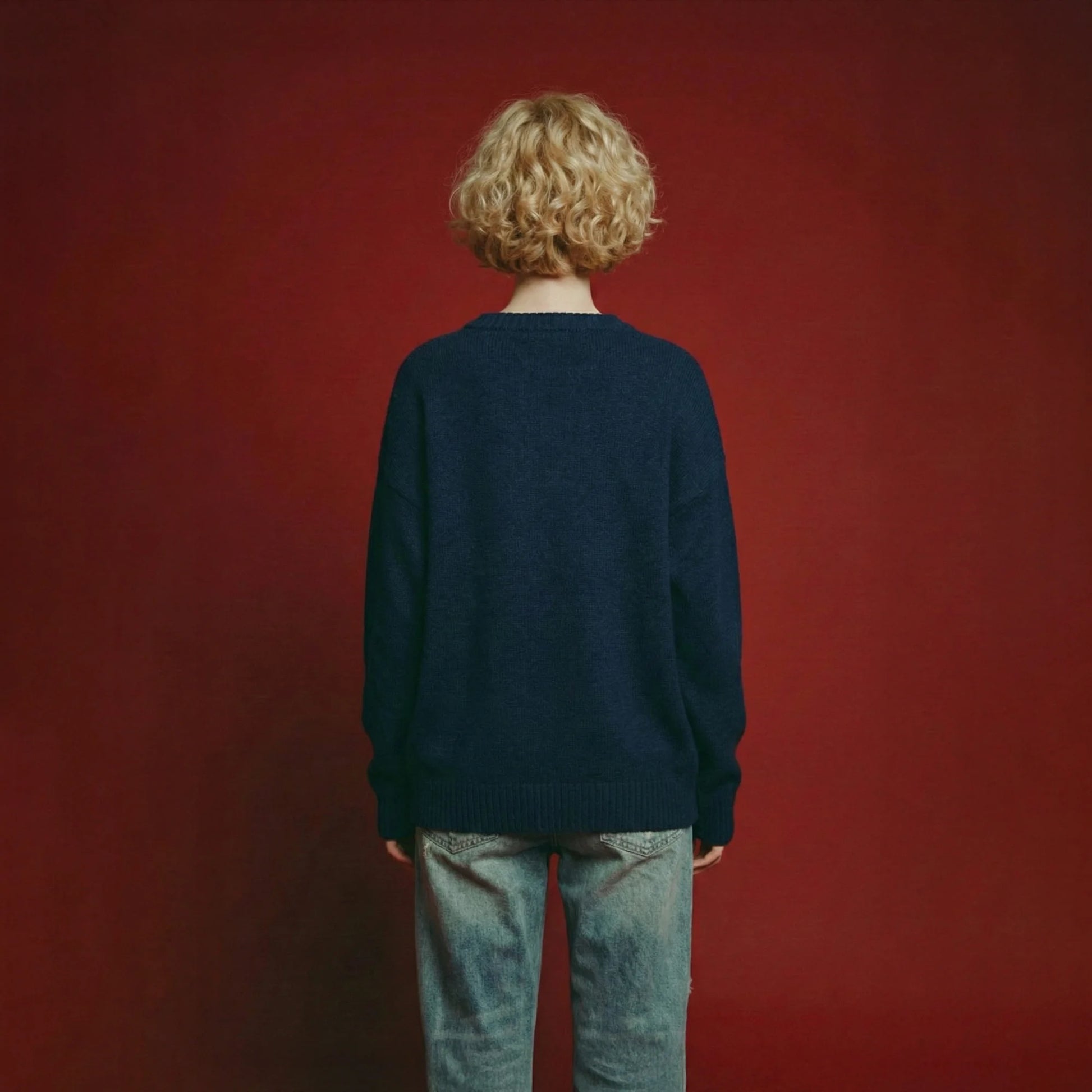 Back view of a model wearing a navy oversized jumper with a plain back and ribbed trims.