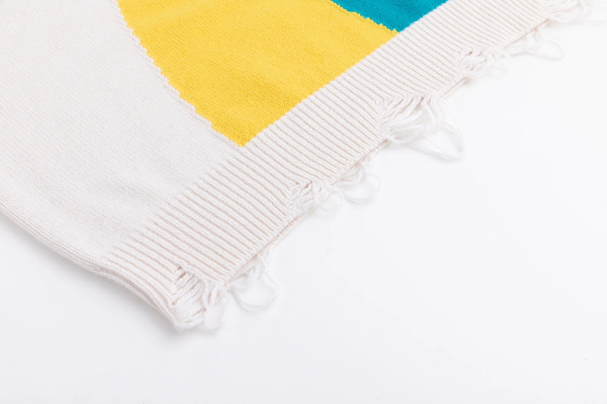 Close-up of the ribbed hem on the ivory cotton and wool blend jumper with distressed details beside the cat jacquard.