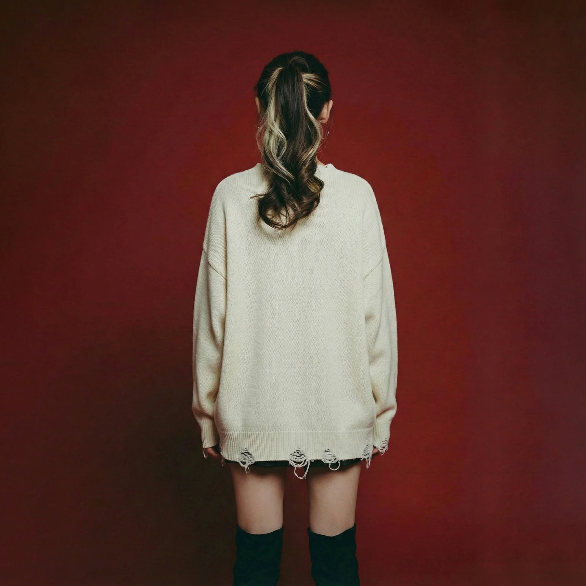 Back view of model wearing an oversized ivory jumper with distressed ribbed trims at the neckline, cuffs and hem.