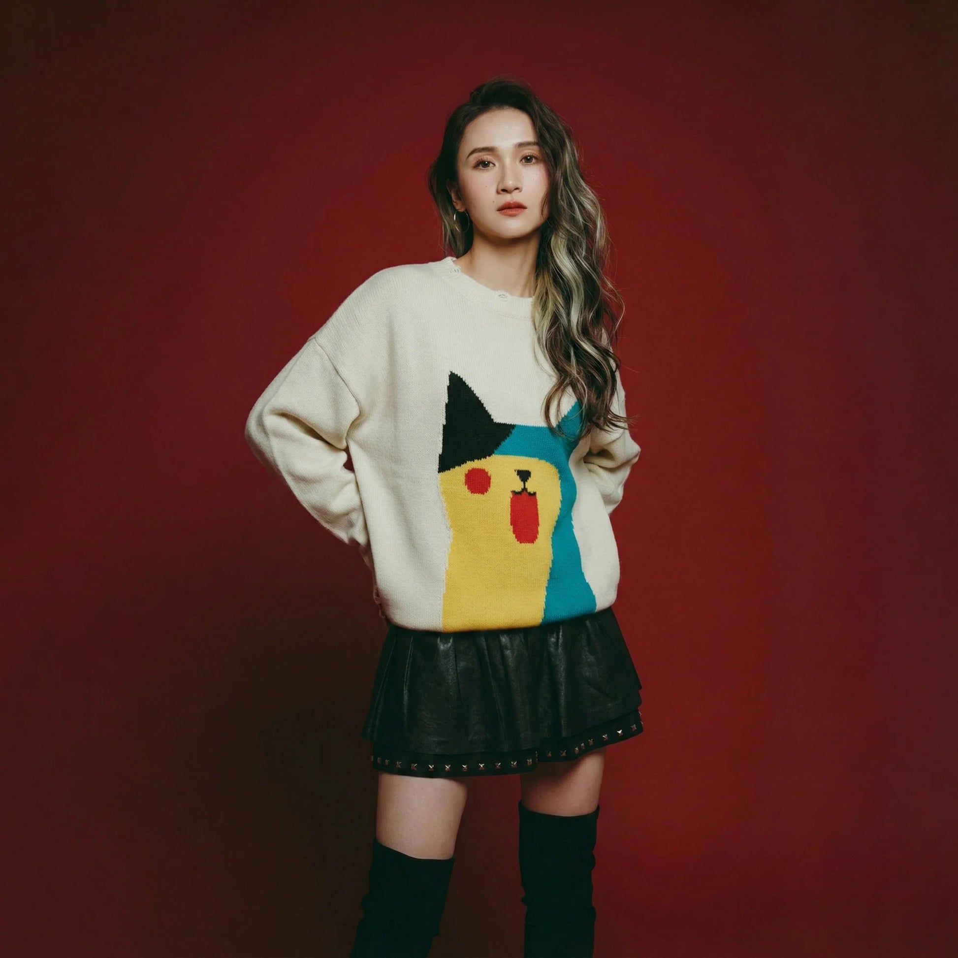 Model wearing an oversized ivory cotton and wool blend jumper with an abstract cat jacquard on the front and distressed ribbed trims.