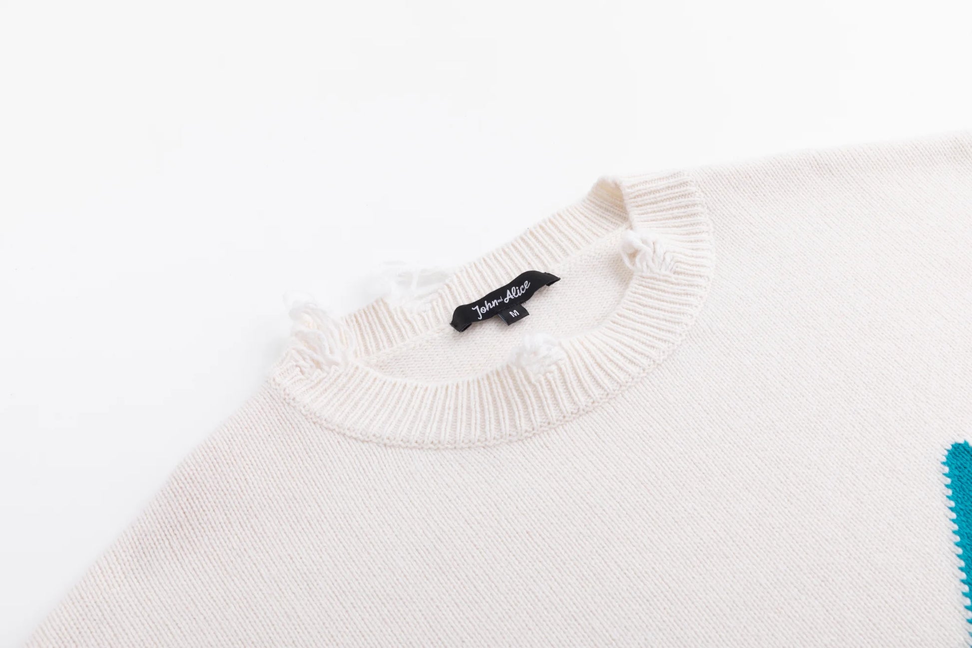 Close-up of the neckline on the ivory jumper with distressed ribbed trim.