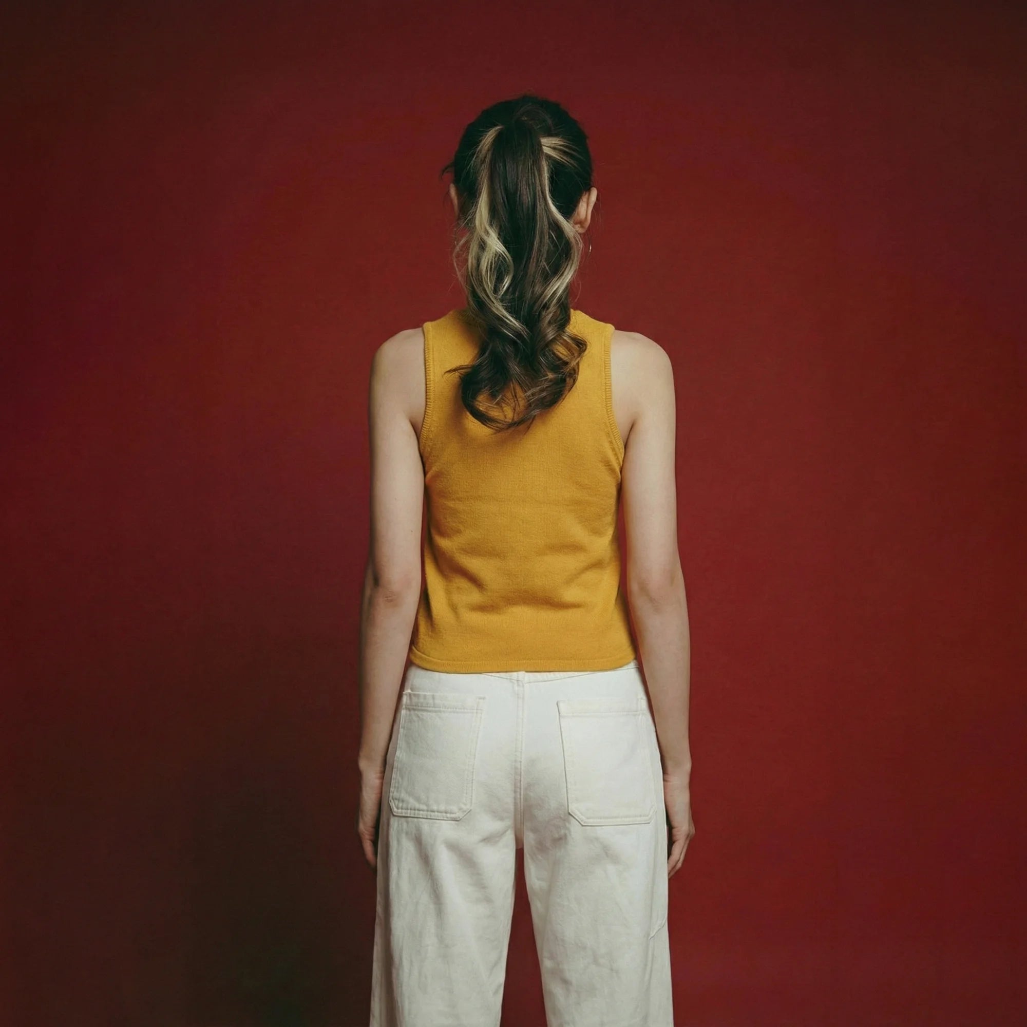 Back view of model wearing a mustard yellow cotton knit tank.
