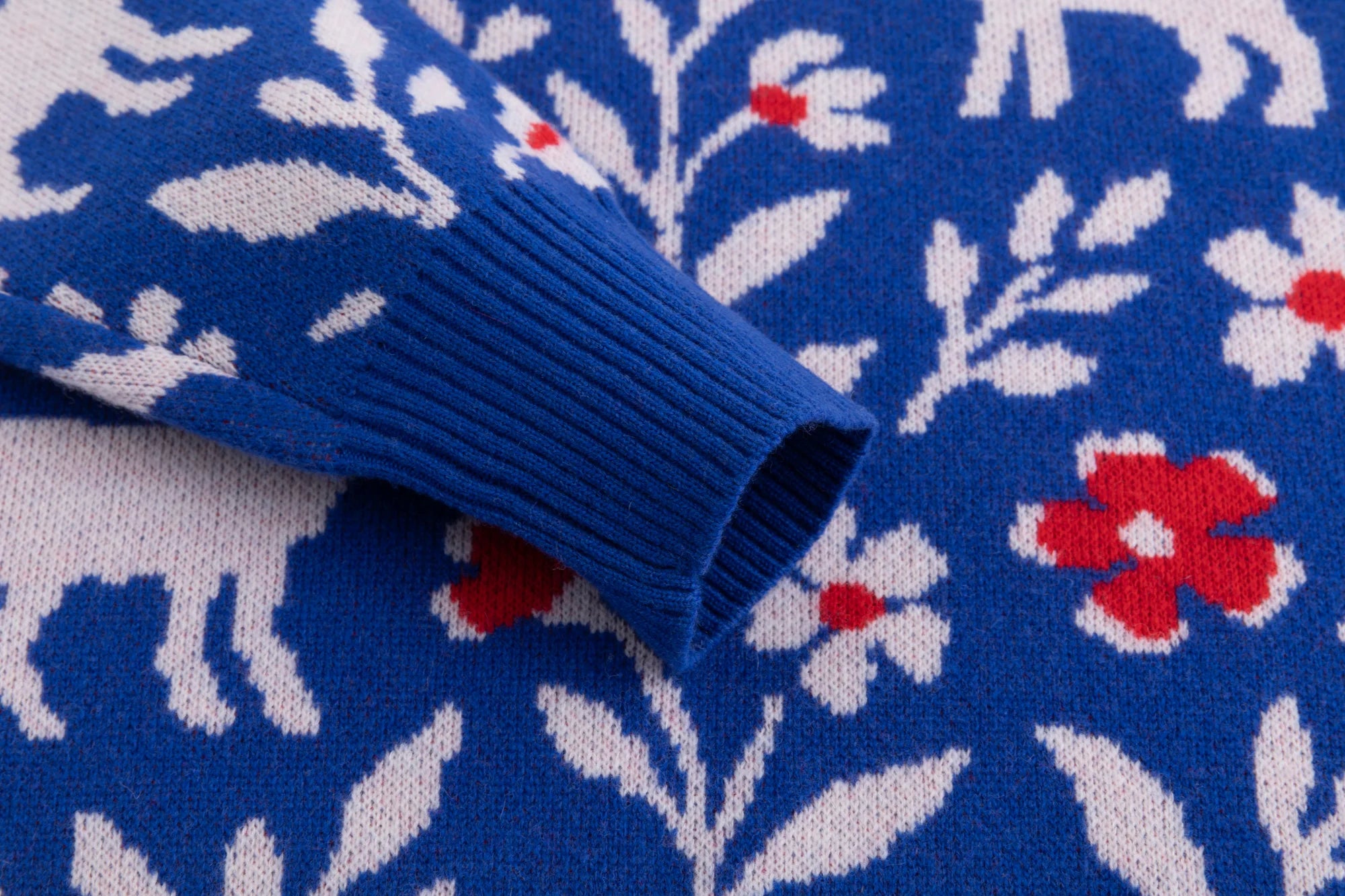 Close-up of the ribbed cuff on the cobalt blue jumper with the sheep and floral jacquard.
