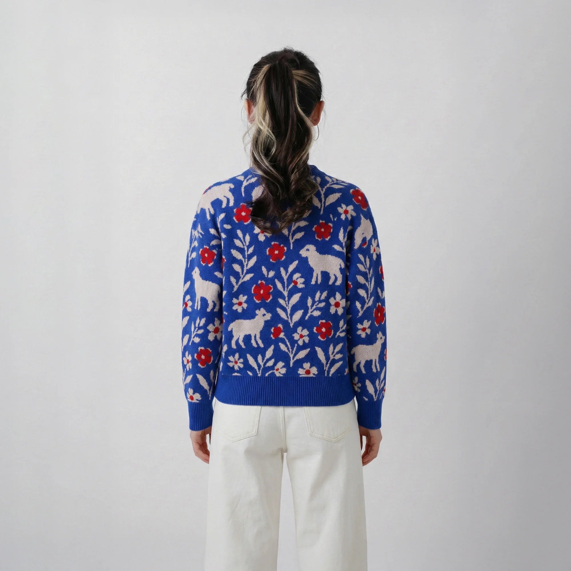 Back view of model wearing a cobalt blue wool jumper with an all-over floral and sheep jacquard.
