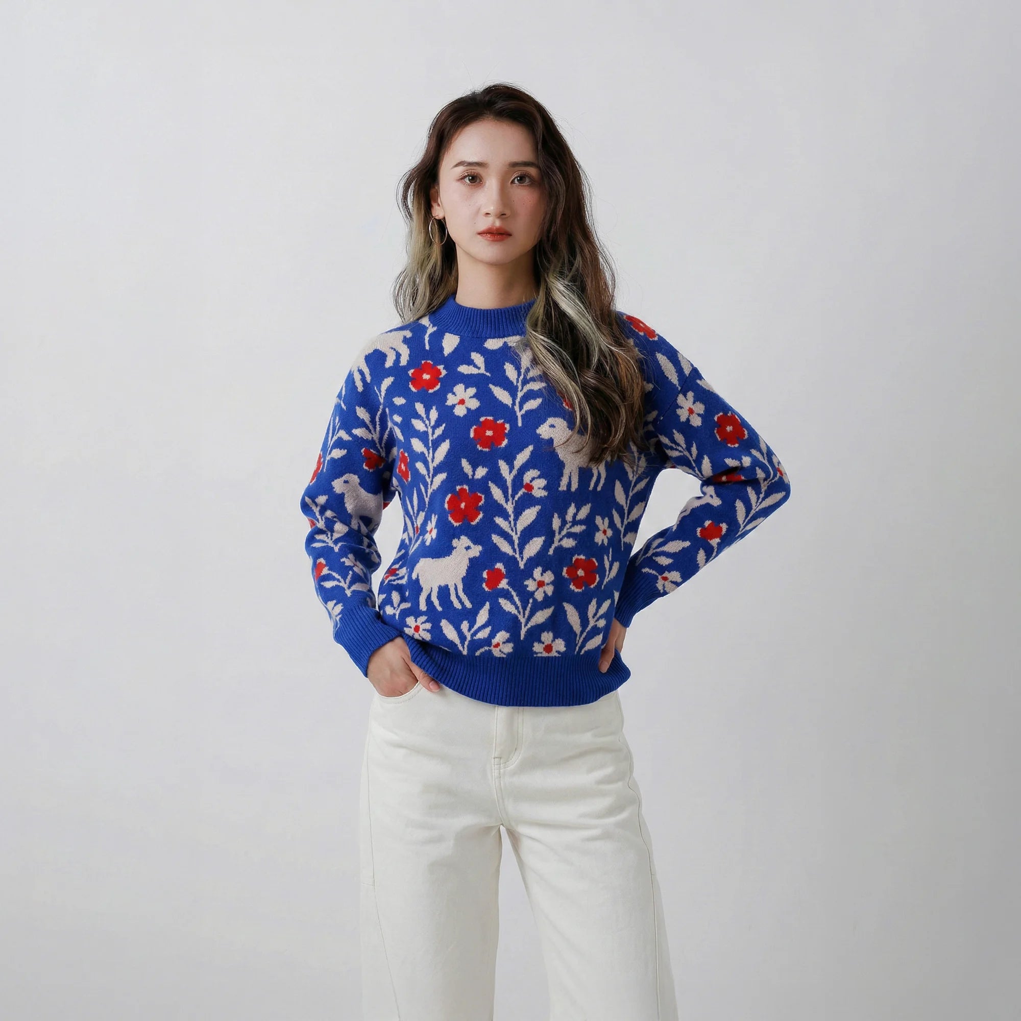 Model wearing a cobalt blue wool jumper with an all-over jacquard of sheep, flowers and leafy branches.