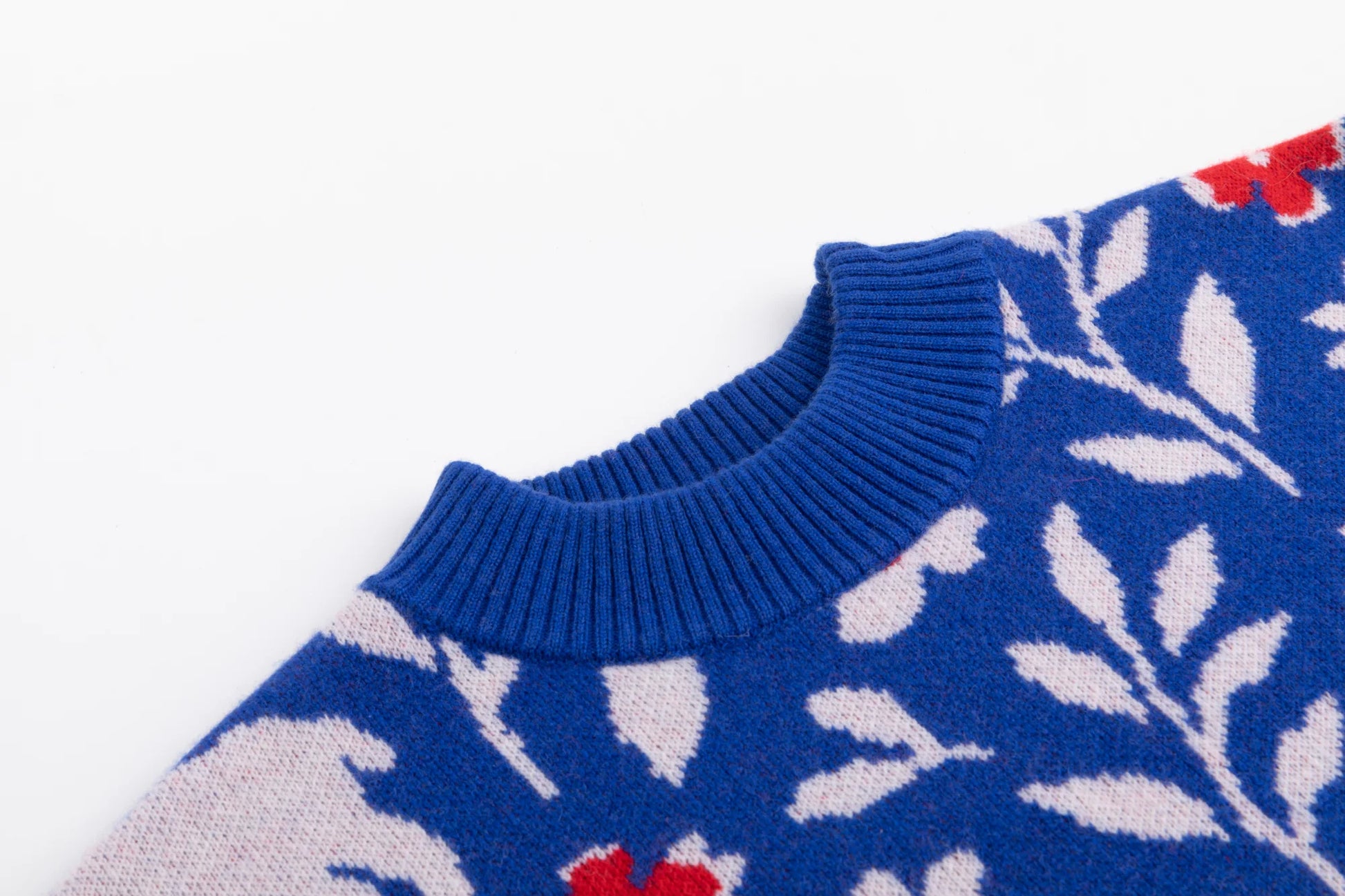 Close-up of the ribbed neckline and shoulder on the cobalt blue jumper with the sheep and floral jacquard.