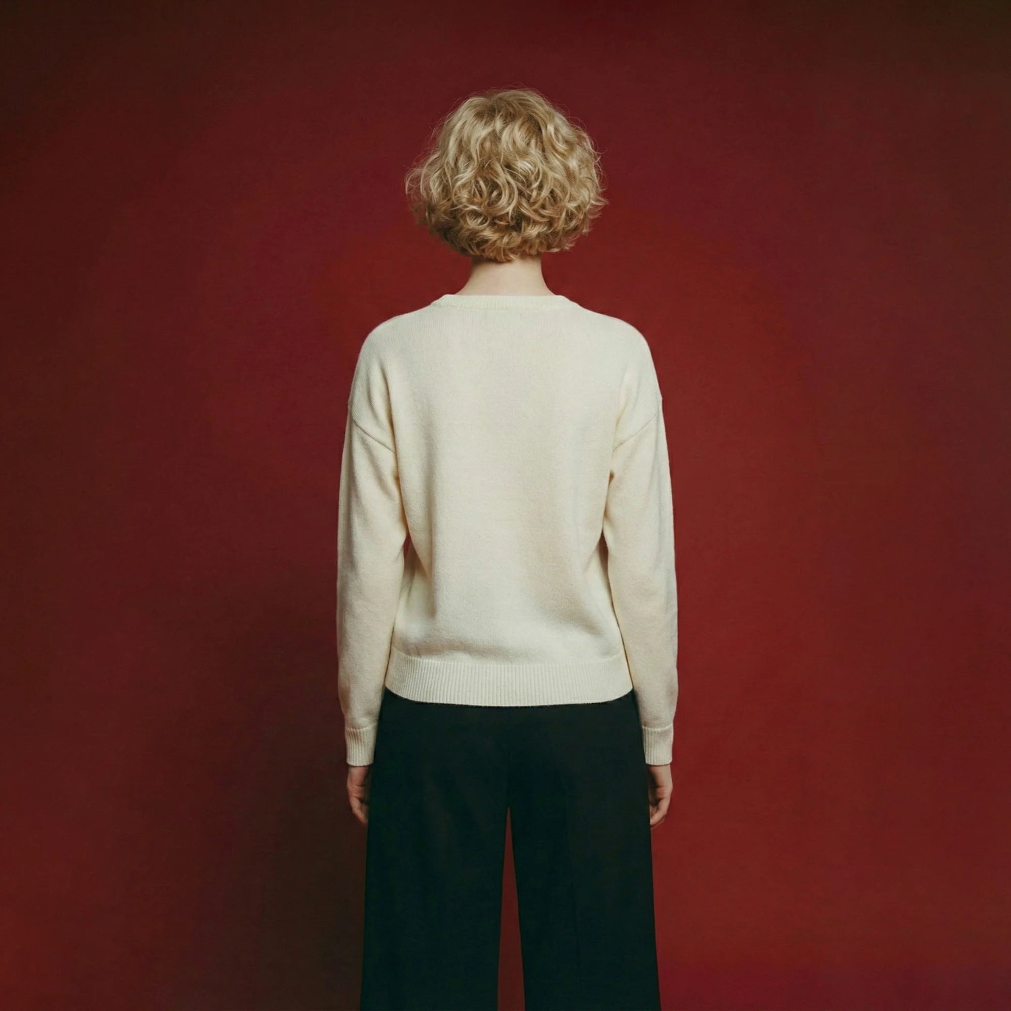 Back view of model wearing an ivory wool jumper with a relaxed drop-shoulder silhouette.
