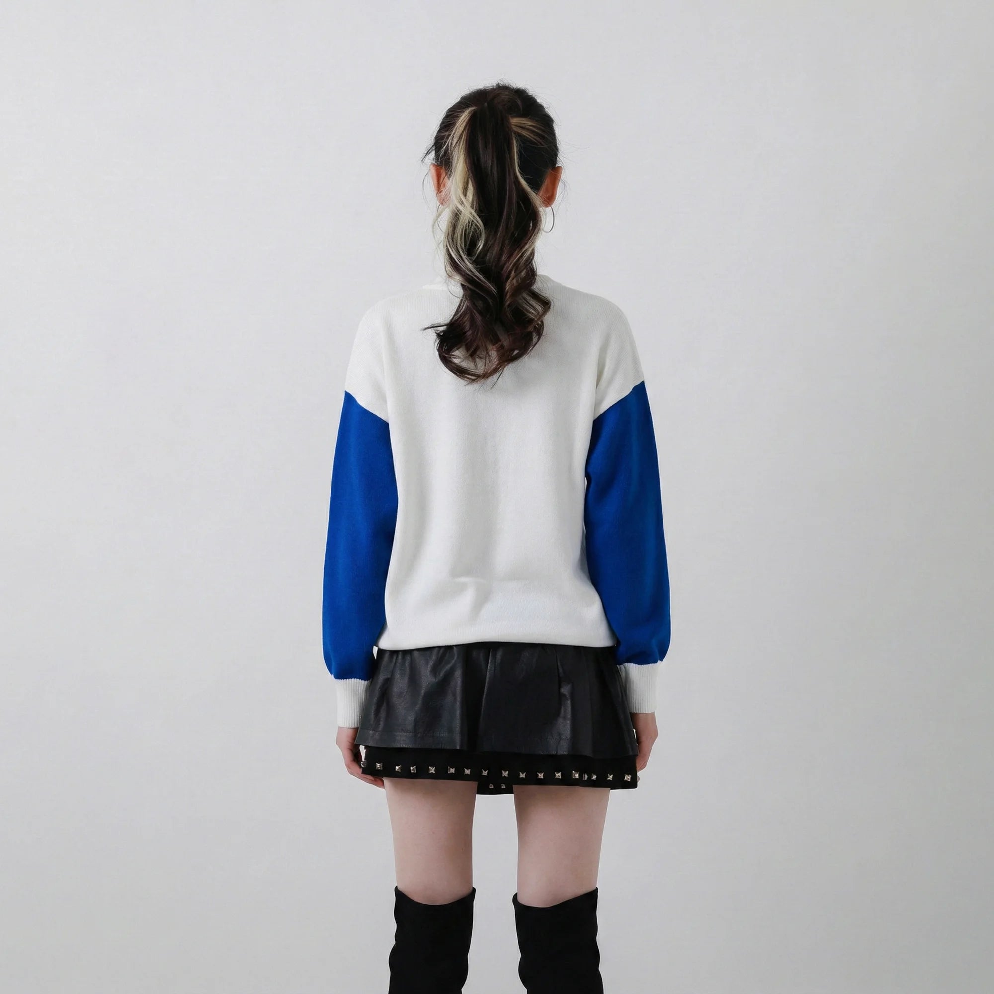 Back view of model wearing a white organic cotton jumper with cobalt blue sleeves and a relaxed dropped-shoulder fit.
