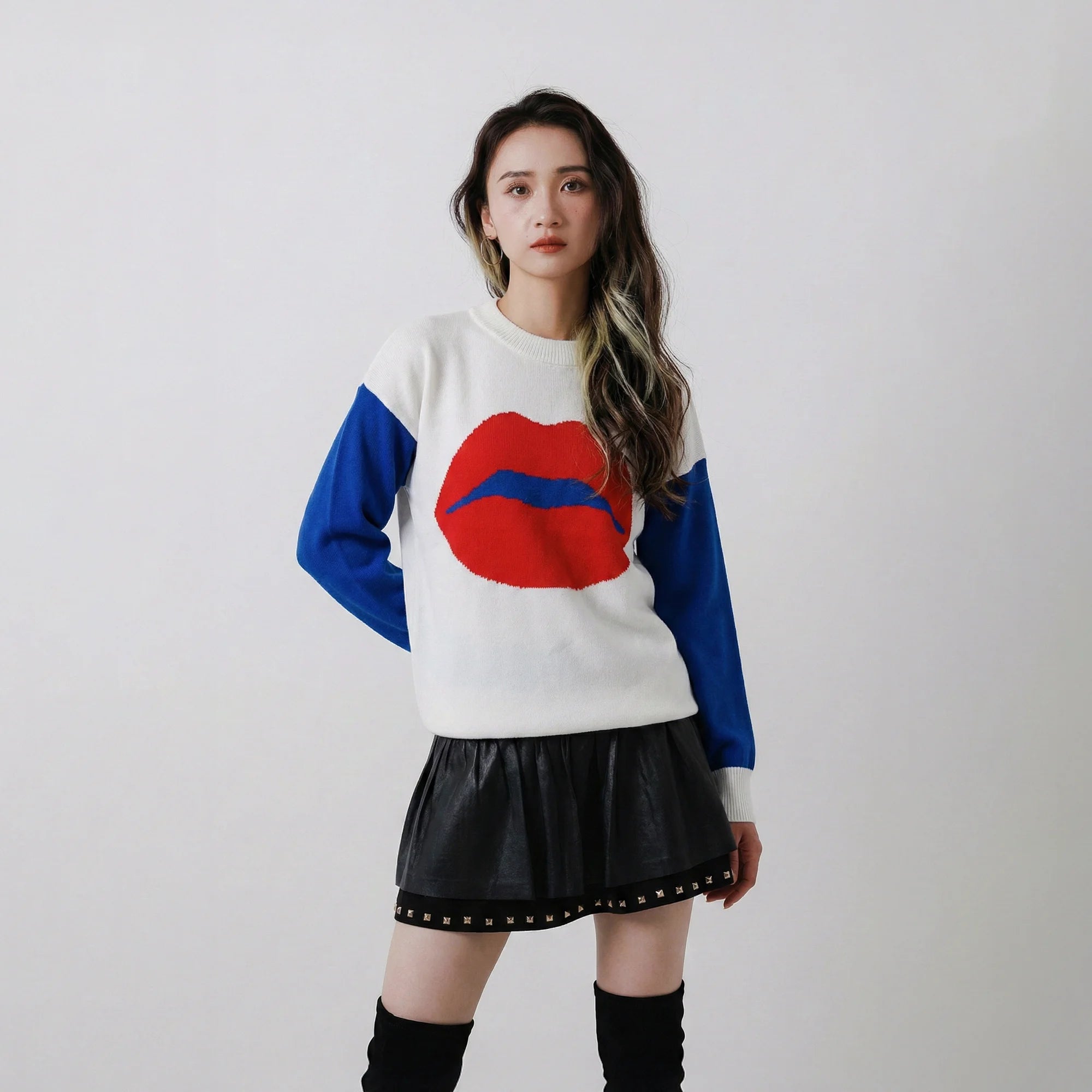 Model wearing a white organic cotton jumper with cobalt blue sleeves and a large red lips motif on the front.