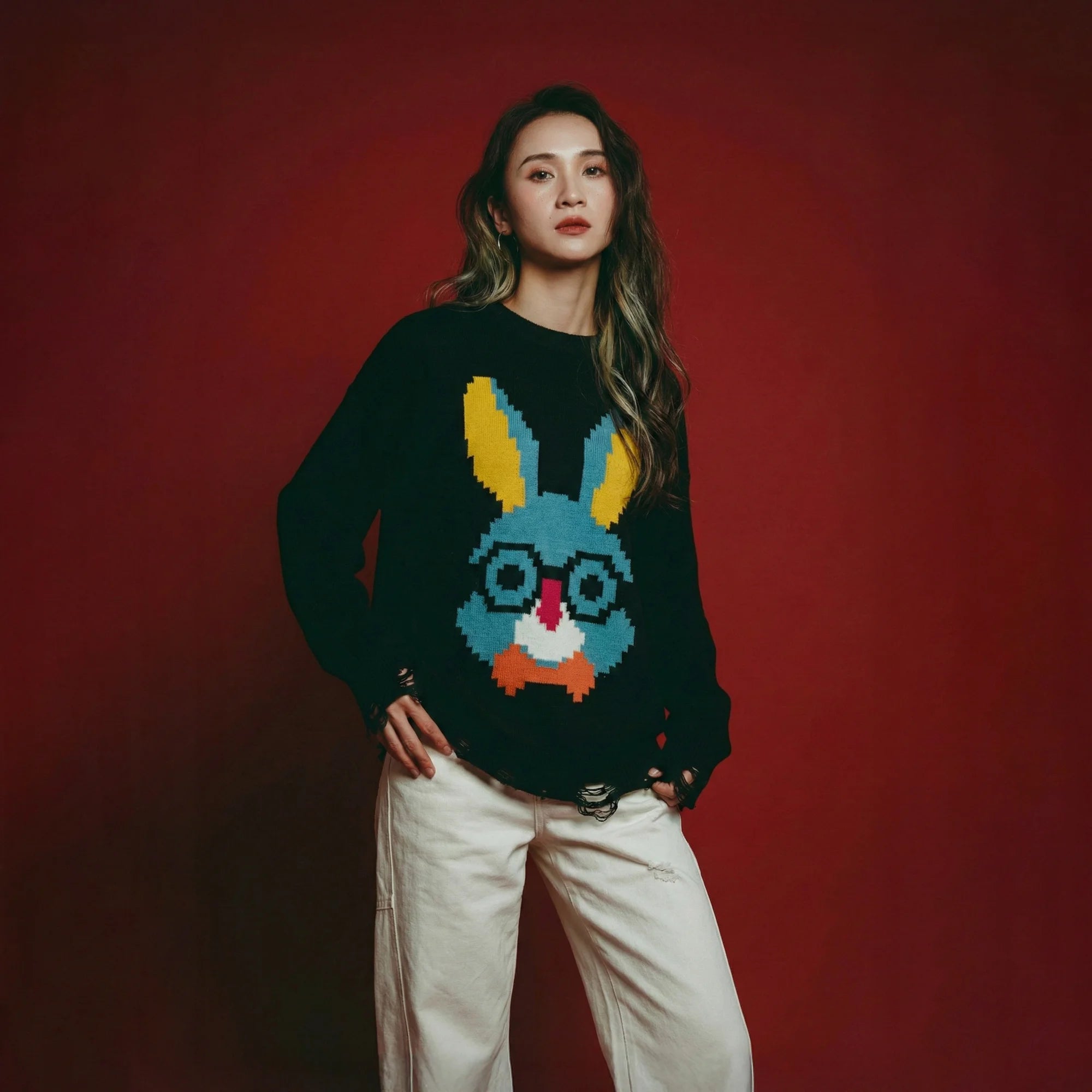 Model wearing a black cotton and wool blend jumper with a pixel-style rabbit face motif on the front and distressed ribbed hem and cuffs.