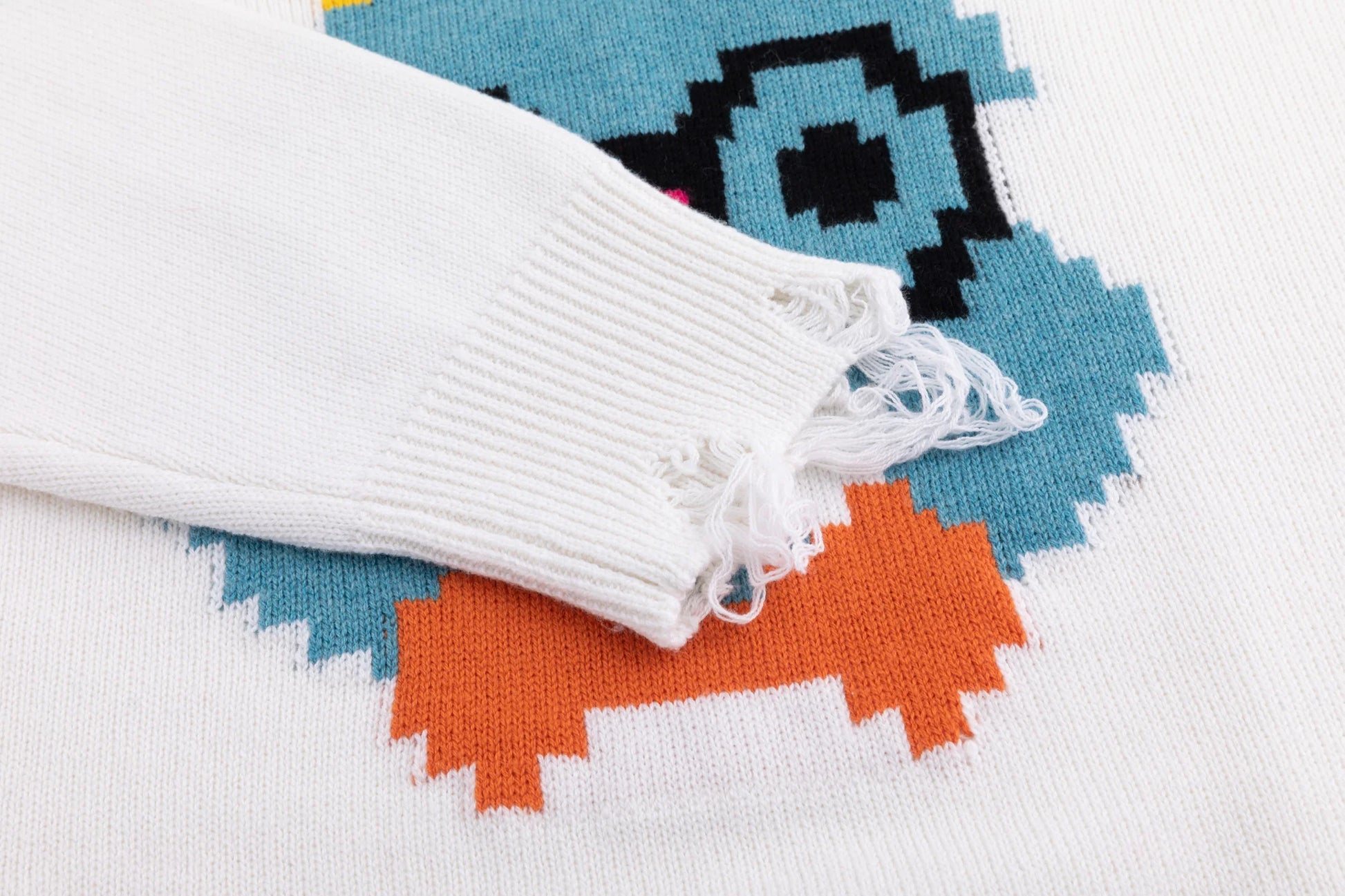 Close-up of the distressed ribbed cuff on the ivory jumper with part of the rabbit motif visible.