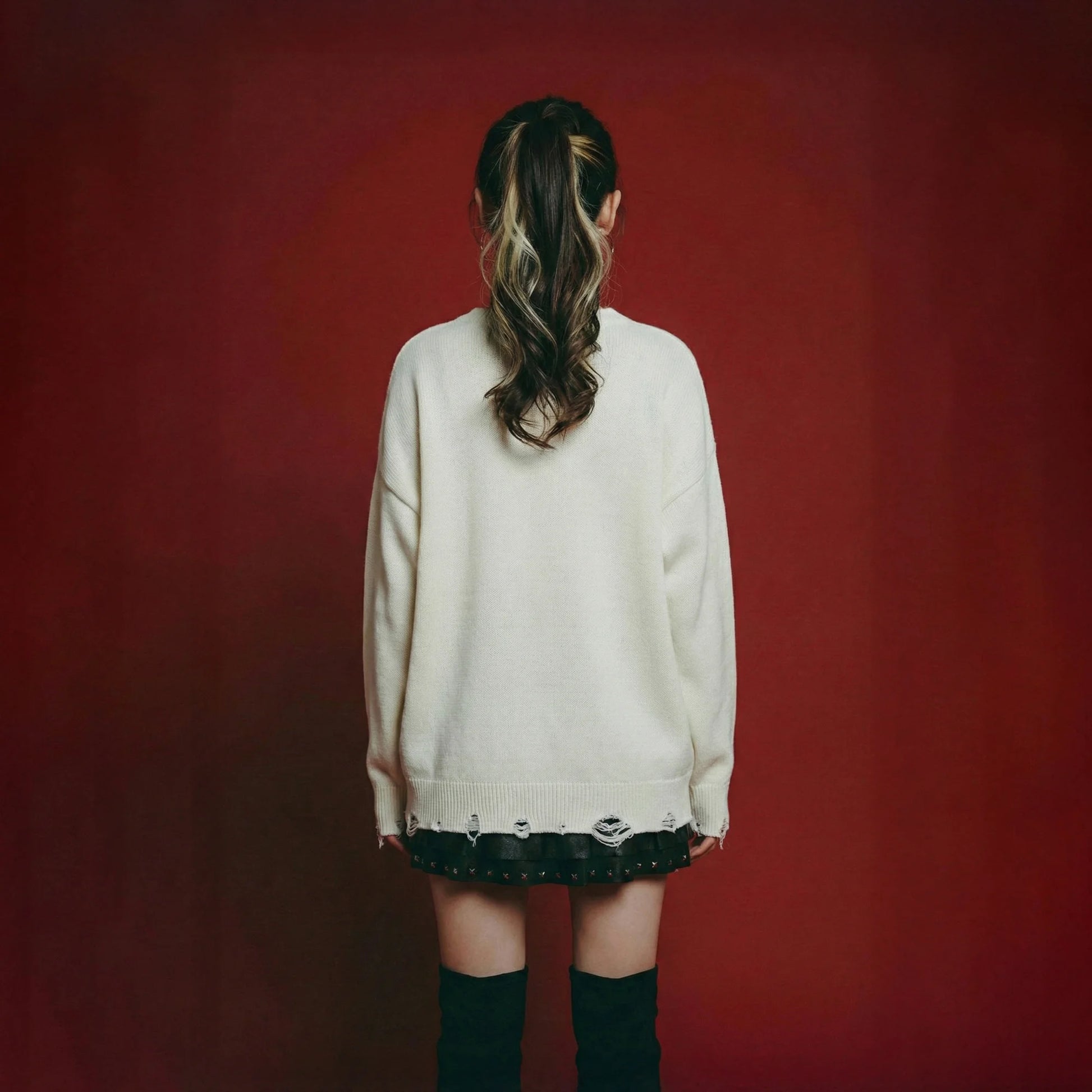 Back view of model wearing an ivory cotton and wool blend jumper with an oversized dropped-shoulder fit and distressed ribbed hem and cuffs.