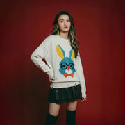 Model wearing an ivory cotton and wool blend jumper with a pixel-style rabbit face motif on the front and distressed ribbed hem and cuffs.